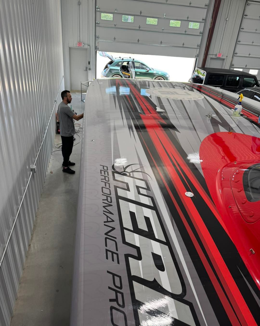 Man standing beside a large red-and-black Hyperformance truck inside a warehouse loading bay