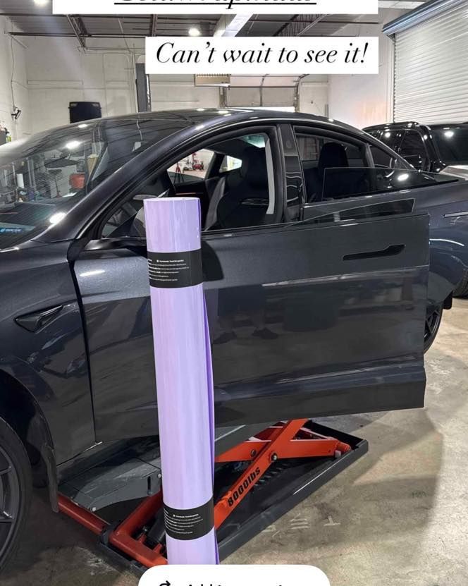 Black car on a shop lift with a purple LED column in front, captioned “Can’t wait to see it!”