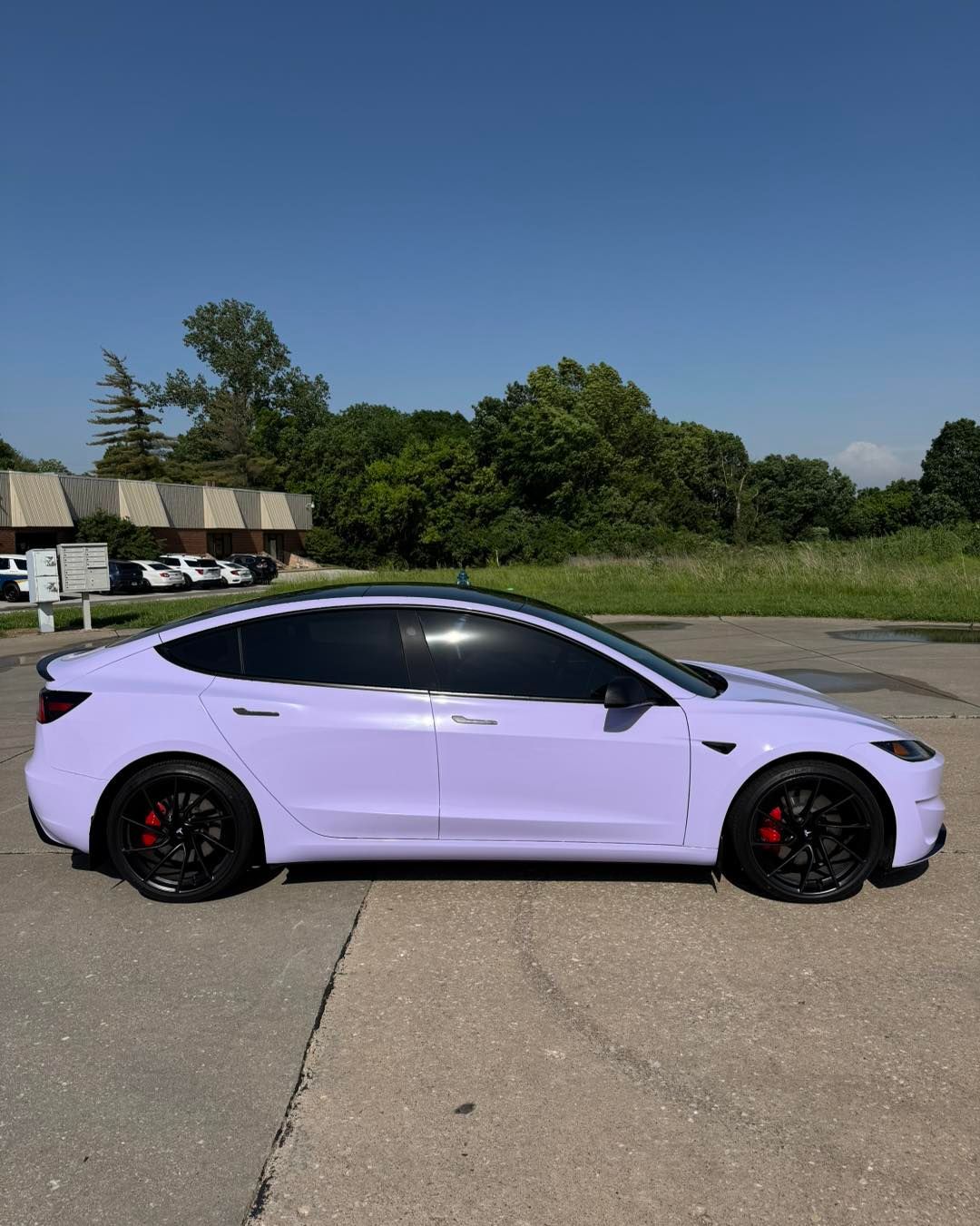 Lavender coupe sports car parked on a concrete lot under a clear blue sky
