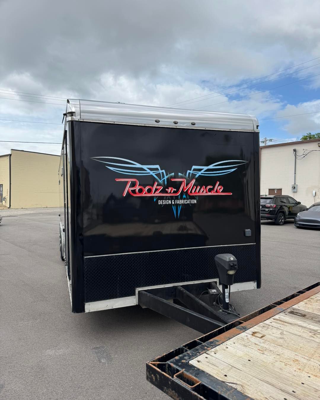 Black enclosed trailer with “Ryder’s Music” logo parked in a lot beside another trailer.