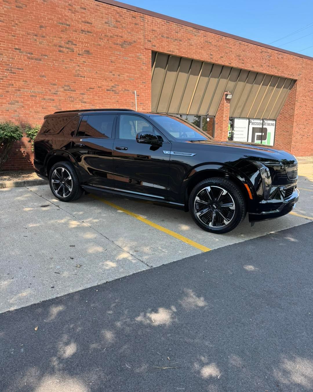 Black SUV parked beside a brick building in daylight