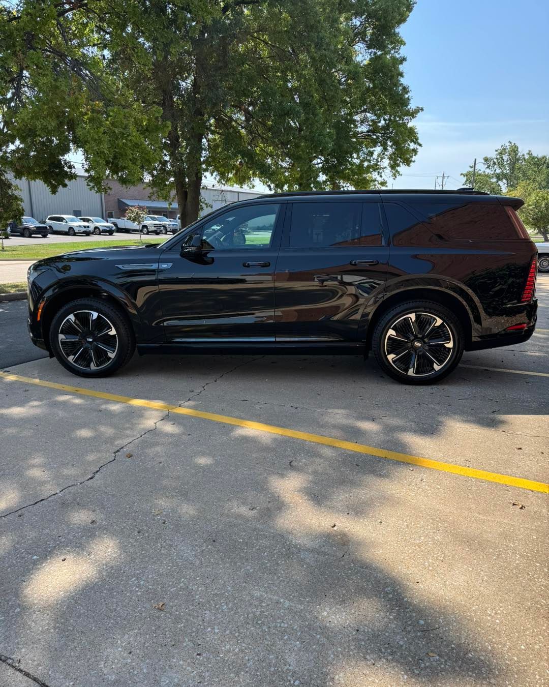 Black SUV parked in a lot with trees and other cars in the background.