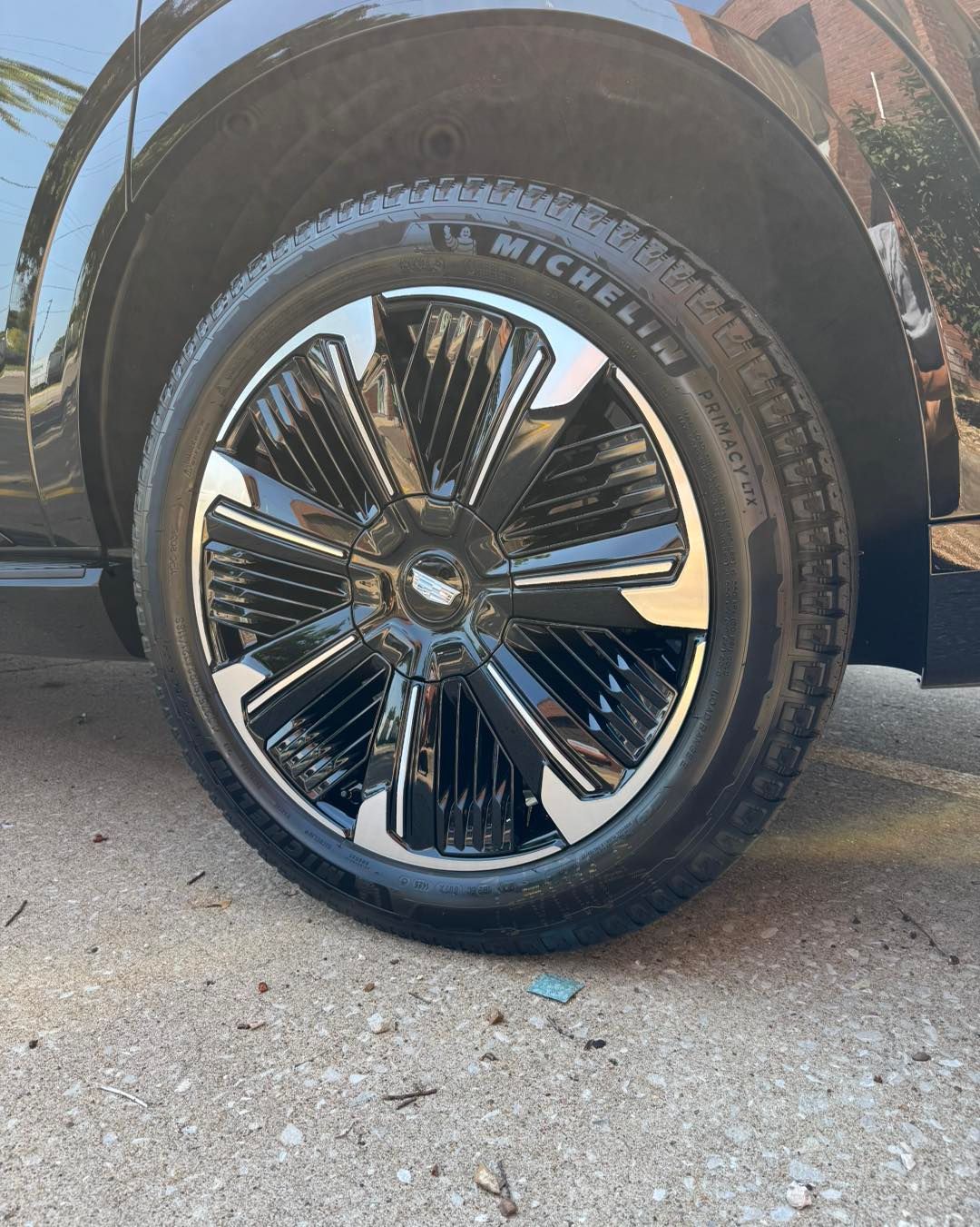Close-up of a black truck wheel with chrome spokes parked on a concrete surface.
