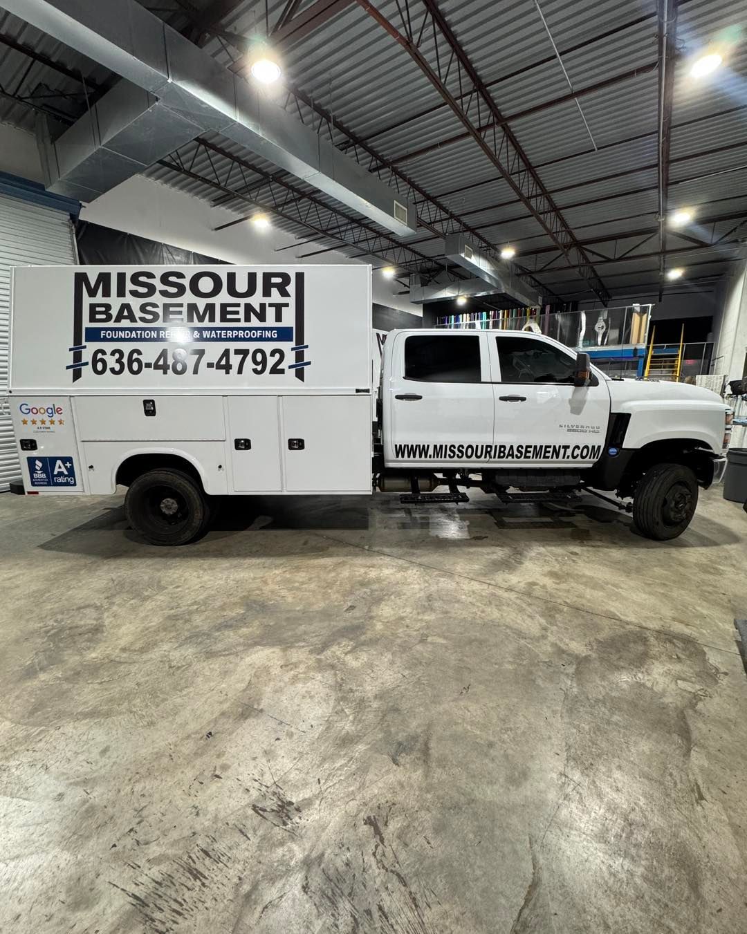 White Missouri Basement Service truck parked indoors in a warehouse-like garage