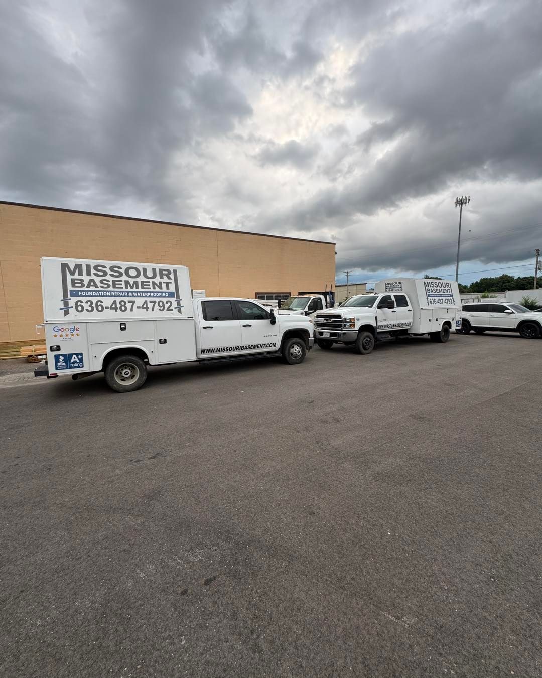 White Missouri Electric service trucks parked by a beige building under cloudy skies.