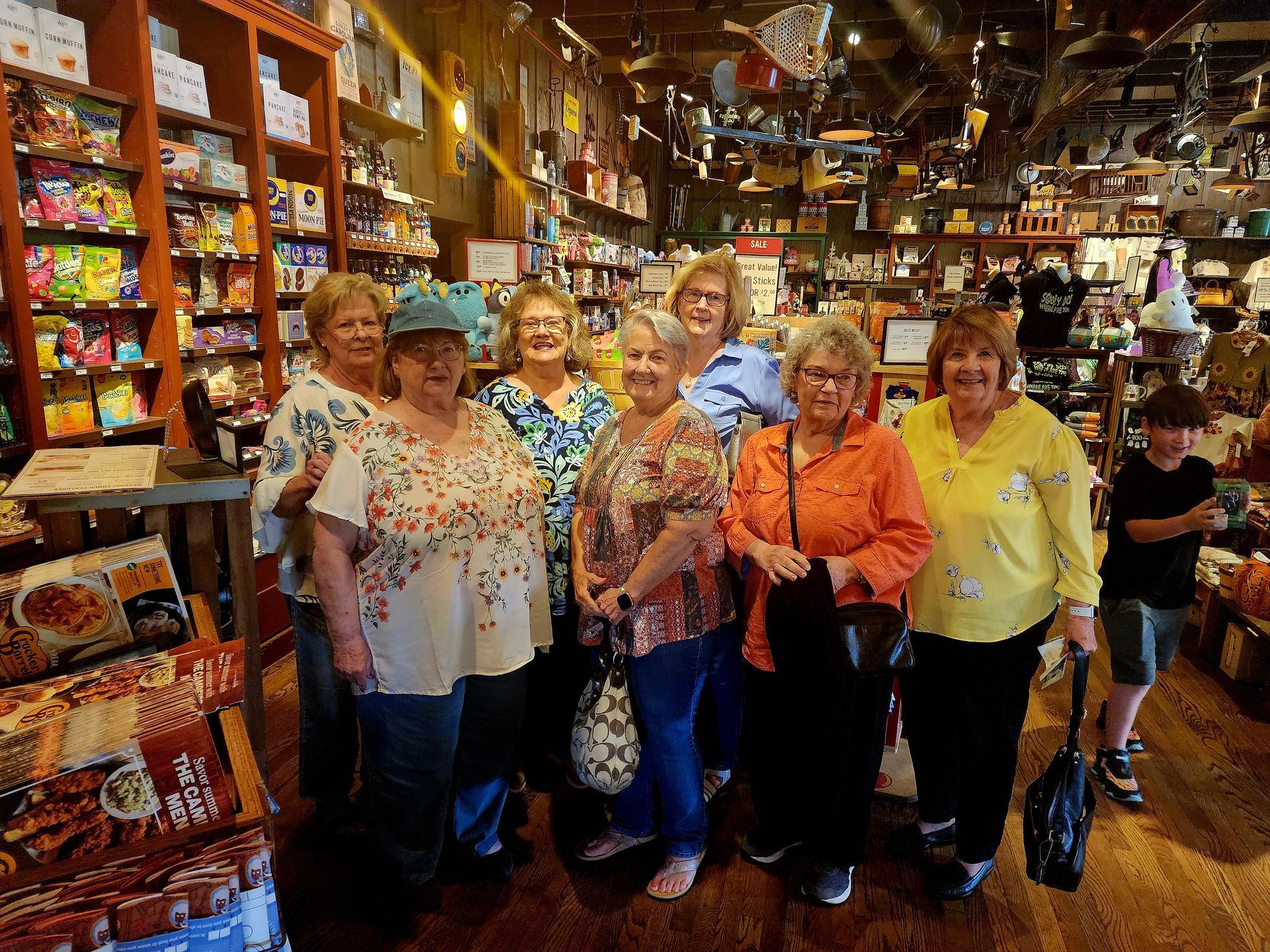 Group of women smiling inside a Cracker Barrel store. They are standing near shelves of merchandise.
