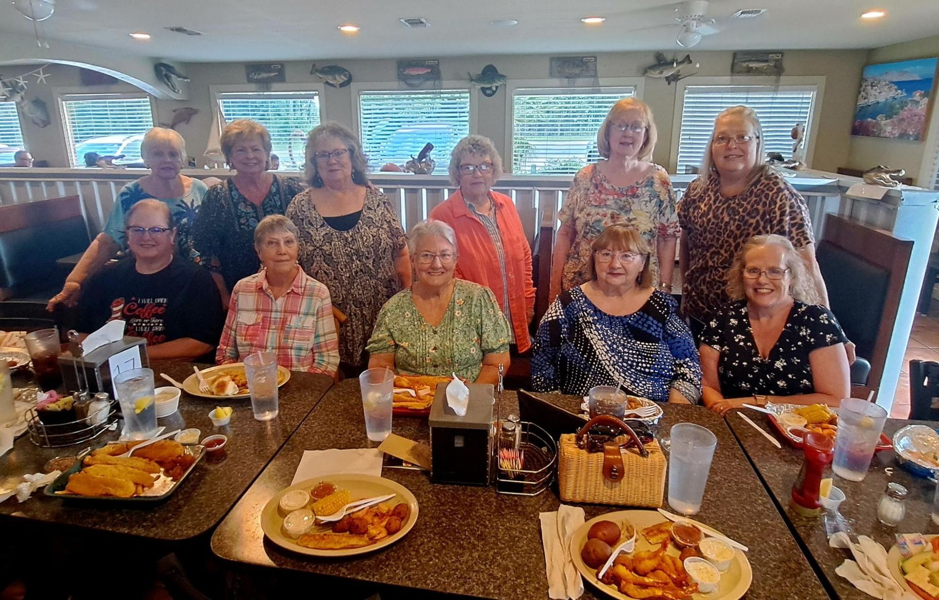 Group of women at a restaurant, seated around a table with food.