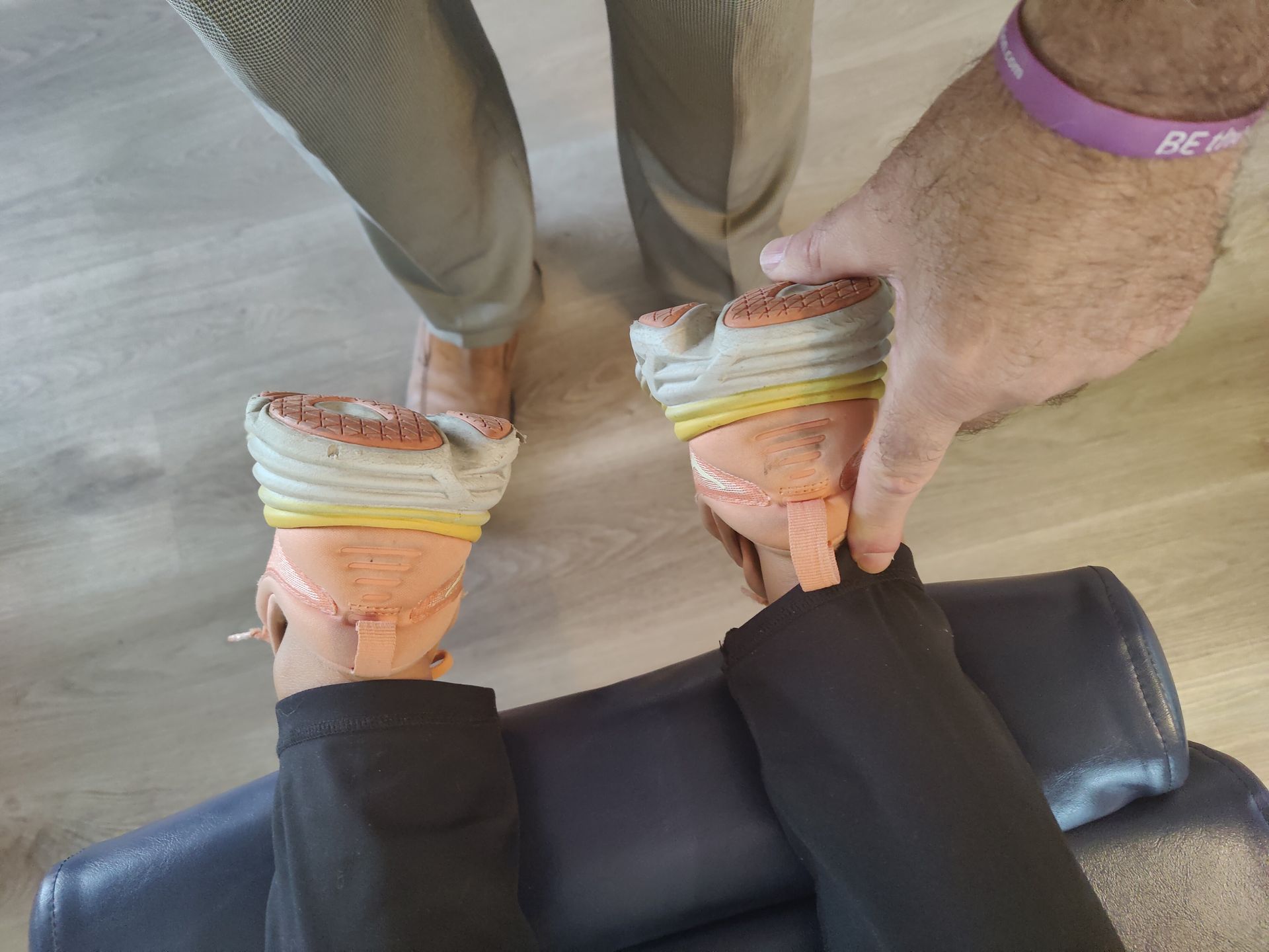 A person is getting their feet stretched by a person with a purple wristband.