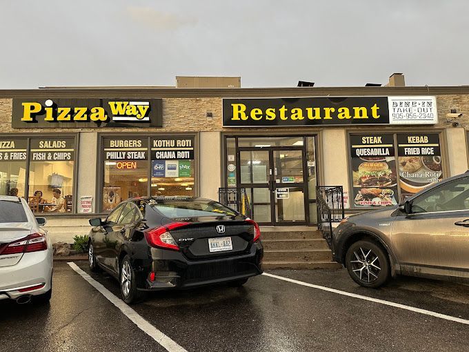 Pizza Way Restaurant storefront with parked cars in front on a rainy day