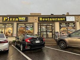 Pizza Way Restaurant storefront with parked cars in front on a rainy day