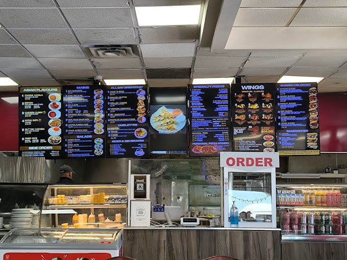 Fast-food counter with bright menu boards, glass display case, and an “ORDER” sign.