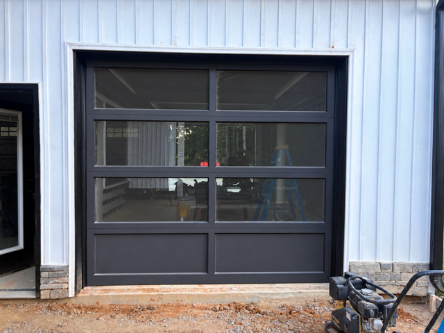 Gray garage-style door on a light metal building with a bicycle at the right edge