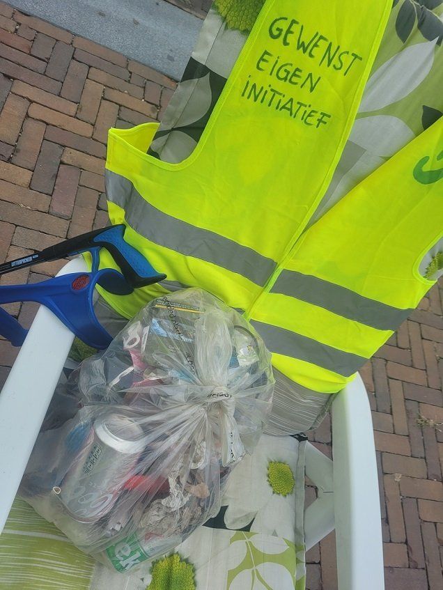 Tuinstoel met een doorzichtige plastic zak waarin gevonden zwerfafval op het Berlijnplein