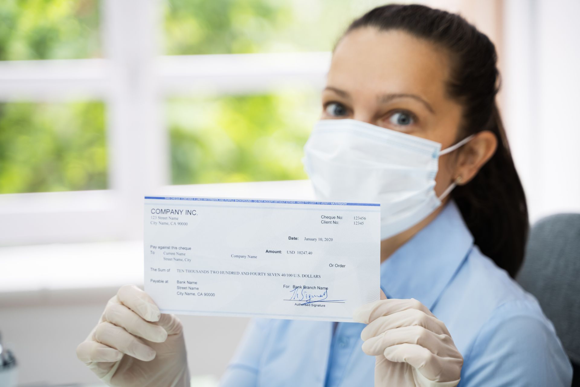 Woman in face mask holding paycheck. Woman in face mask holding paycheck.