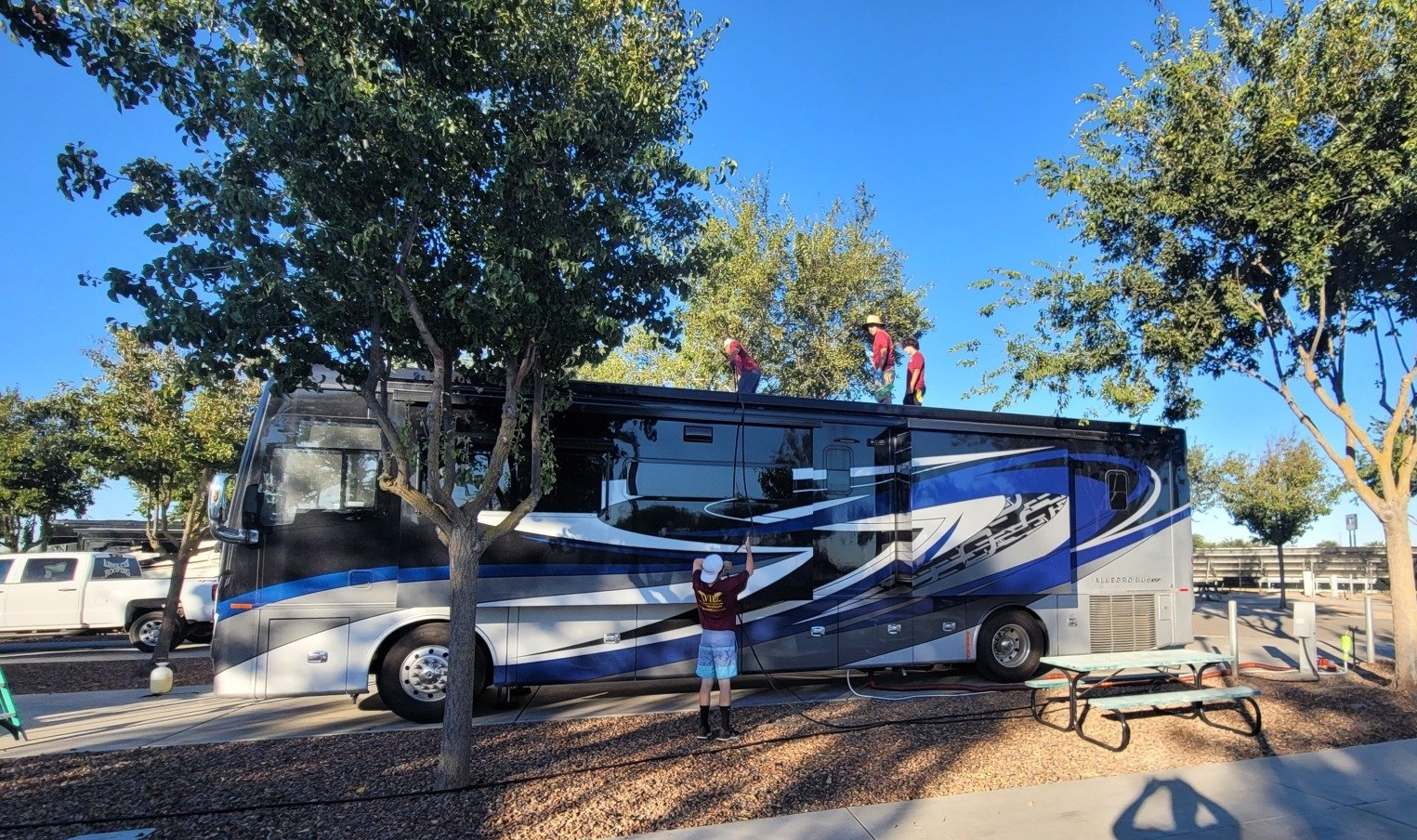 A person is standing on top of a rv parked in a parking lot.