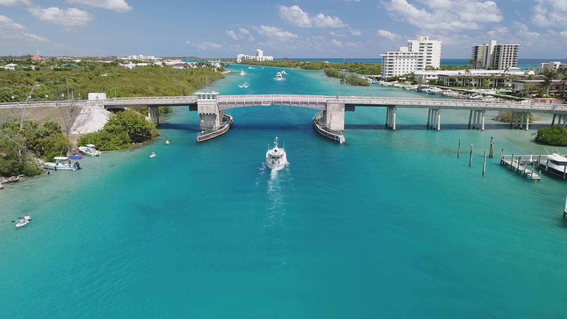 A boat is going under a bridge over a body of water.