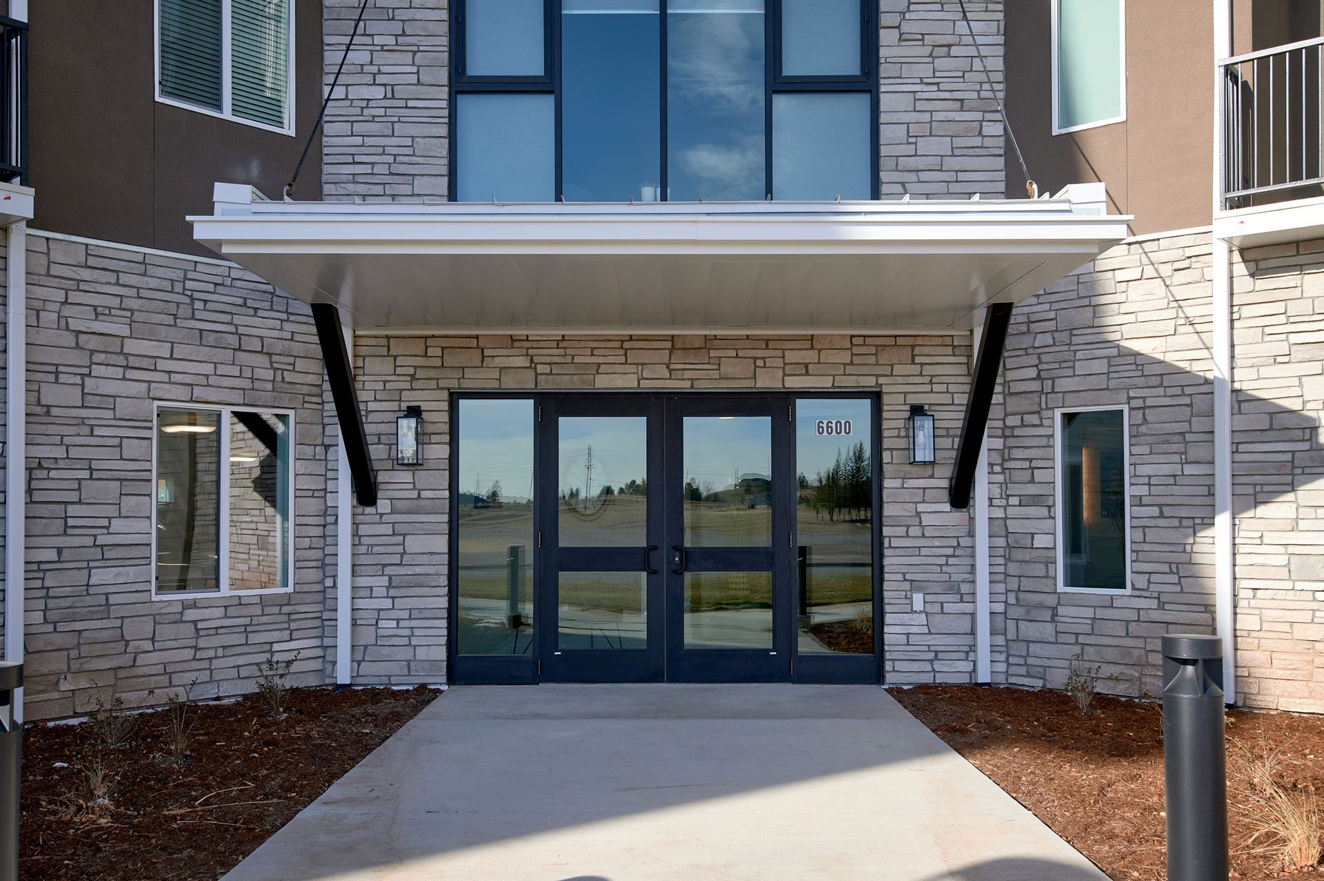 Building entrance with glass double doors, stone walls, and a covered walkway