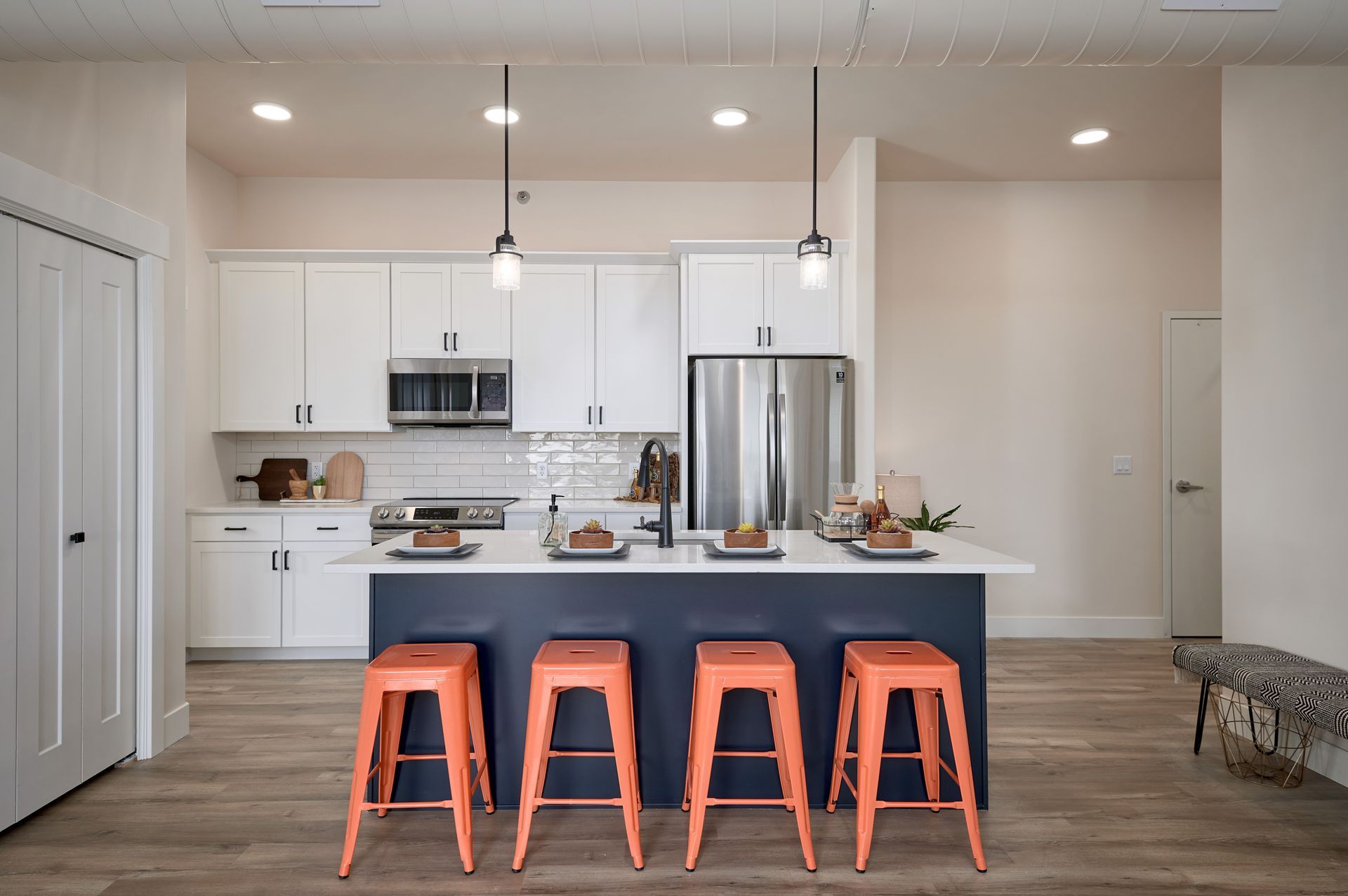 Modern kitchen with white cabinets, gray island, and four orange stools