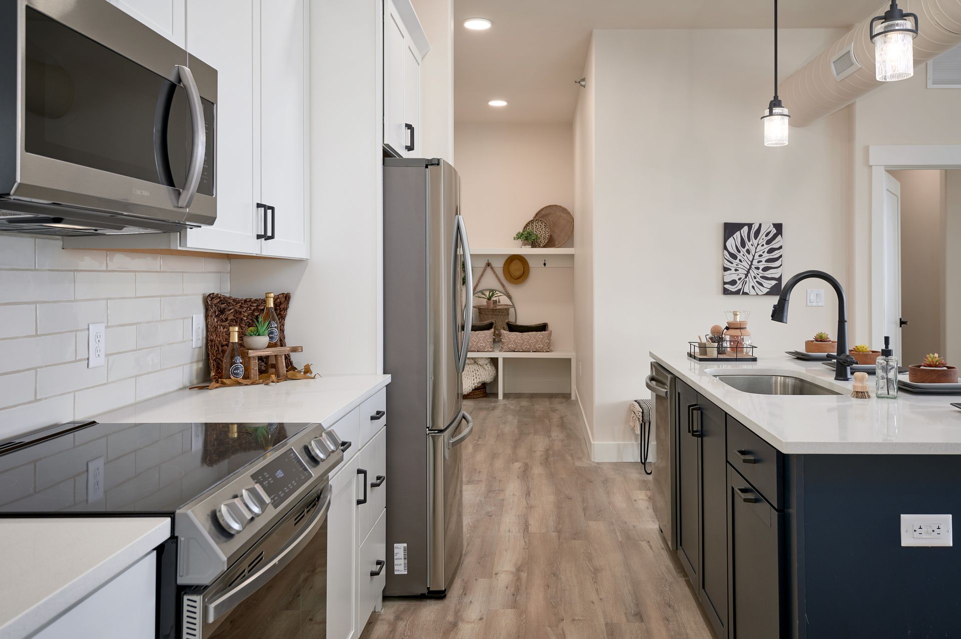 Modern kitchen with stainless appliances, dark island, white cabinets, and wood floors