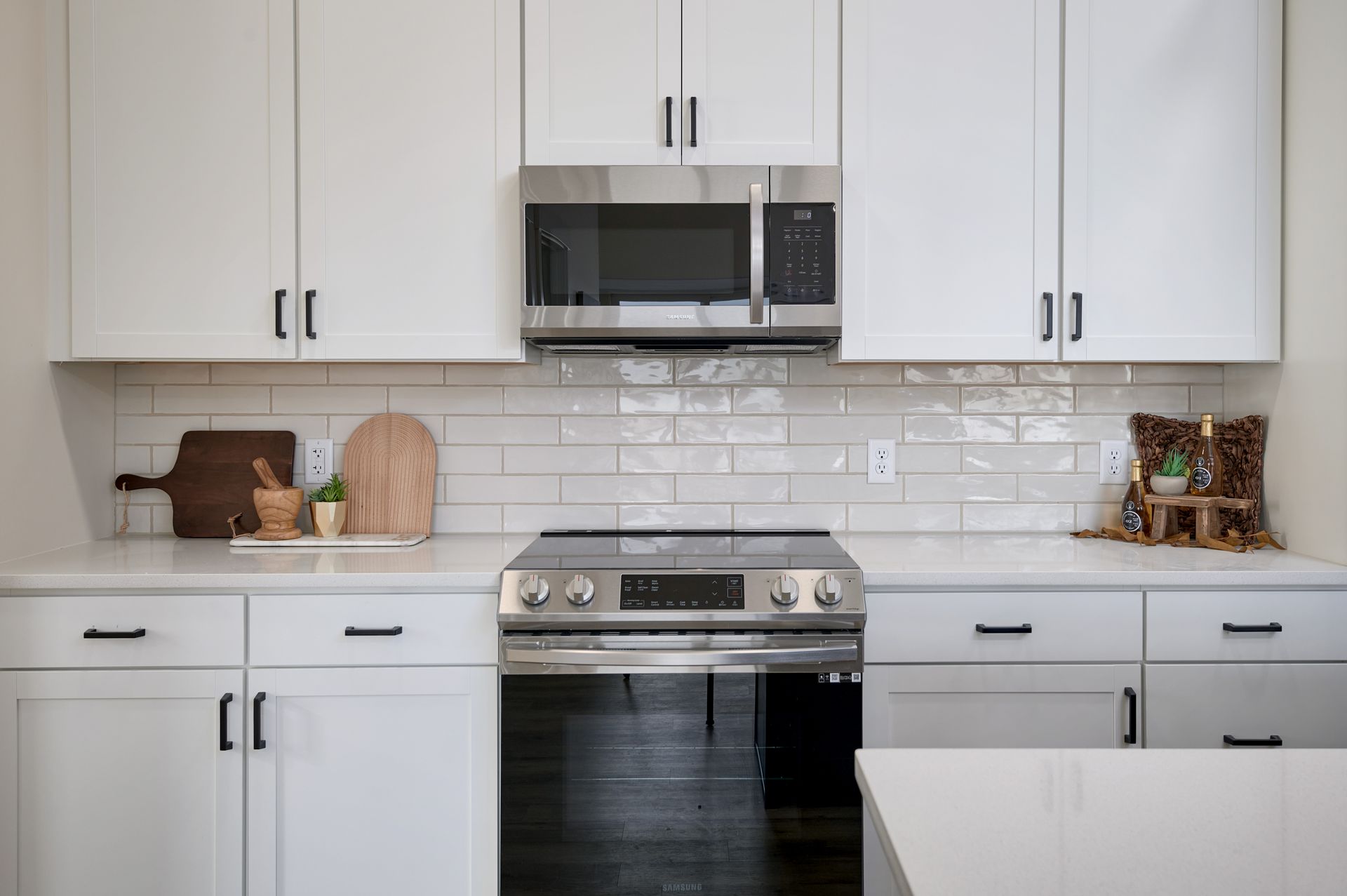 Modern white kitchen with black appliances, marble backsplash, and countertops