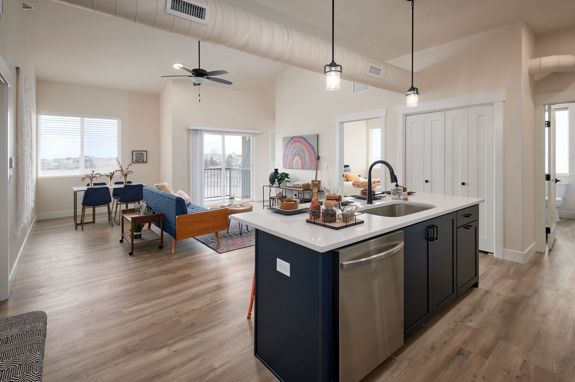 Open-concept kitchen and dining area with island, dark cabinets, white walls, and light wood floors.