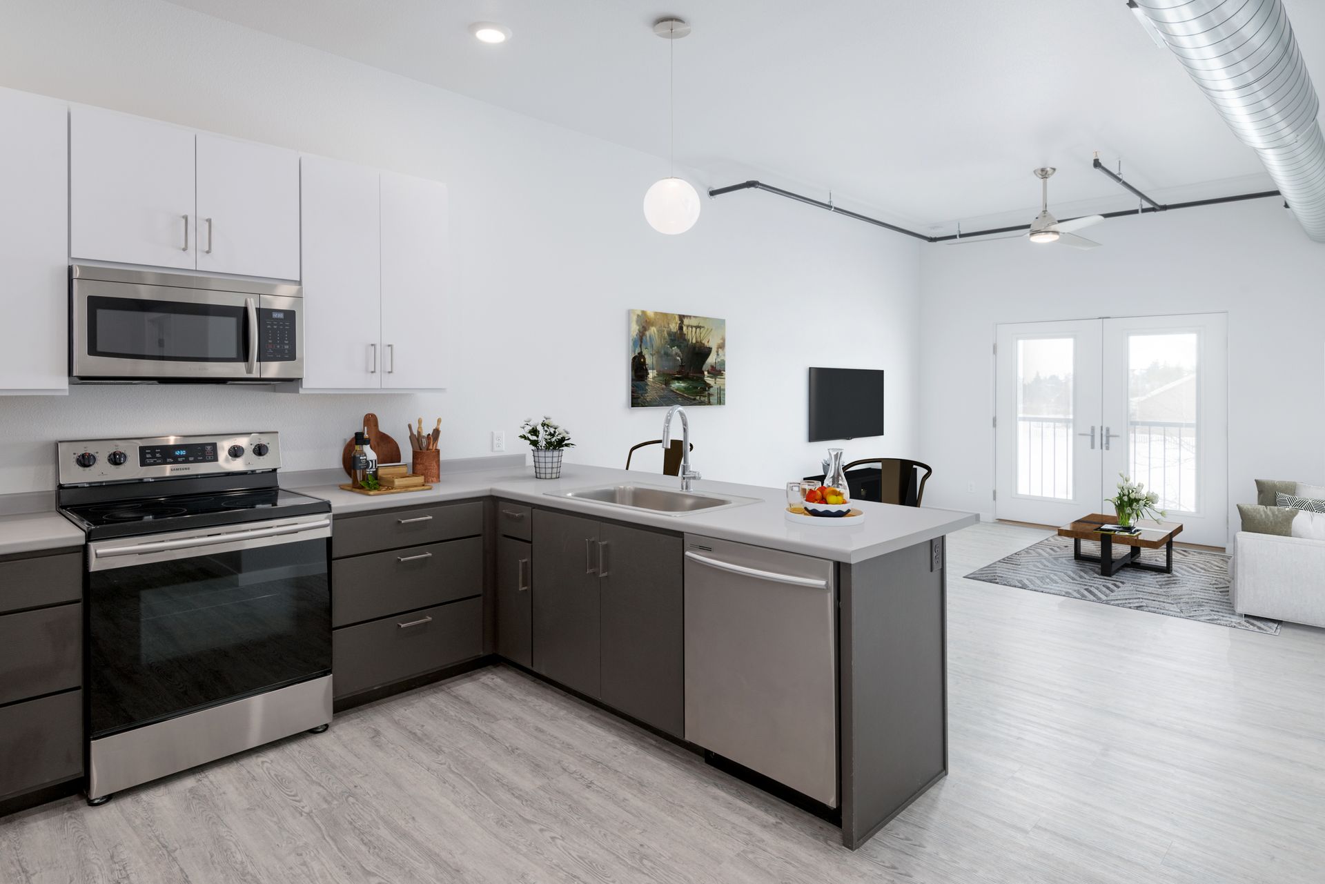 Modern white kitchen with dark cabinets, stainless steel appliances, and a bright open dining area