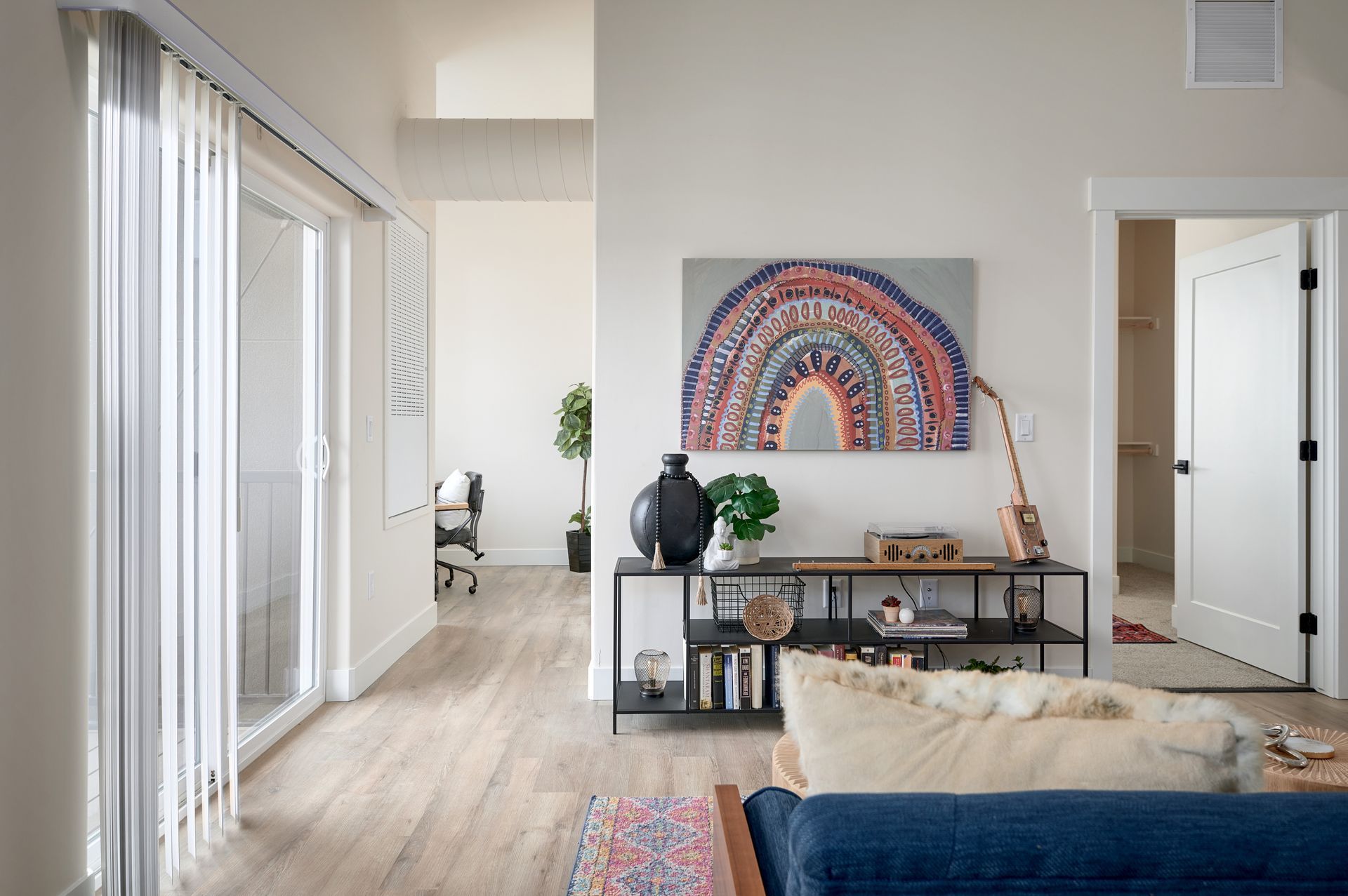 Bright living room with sliding glass doors, wall art, console table, and blue sofa