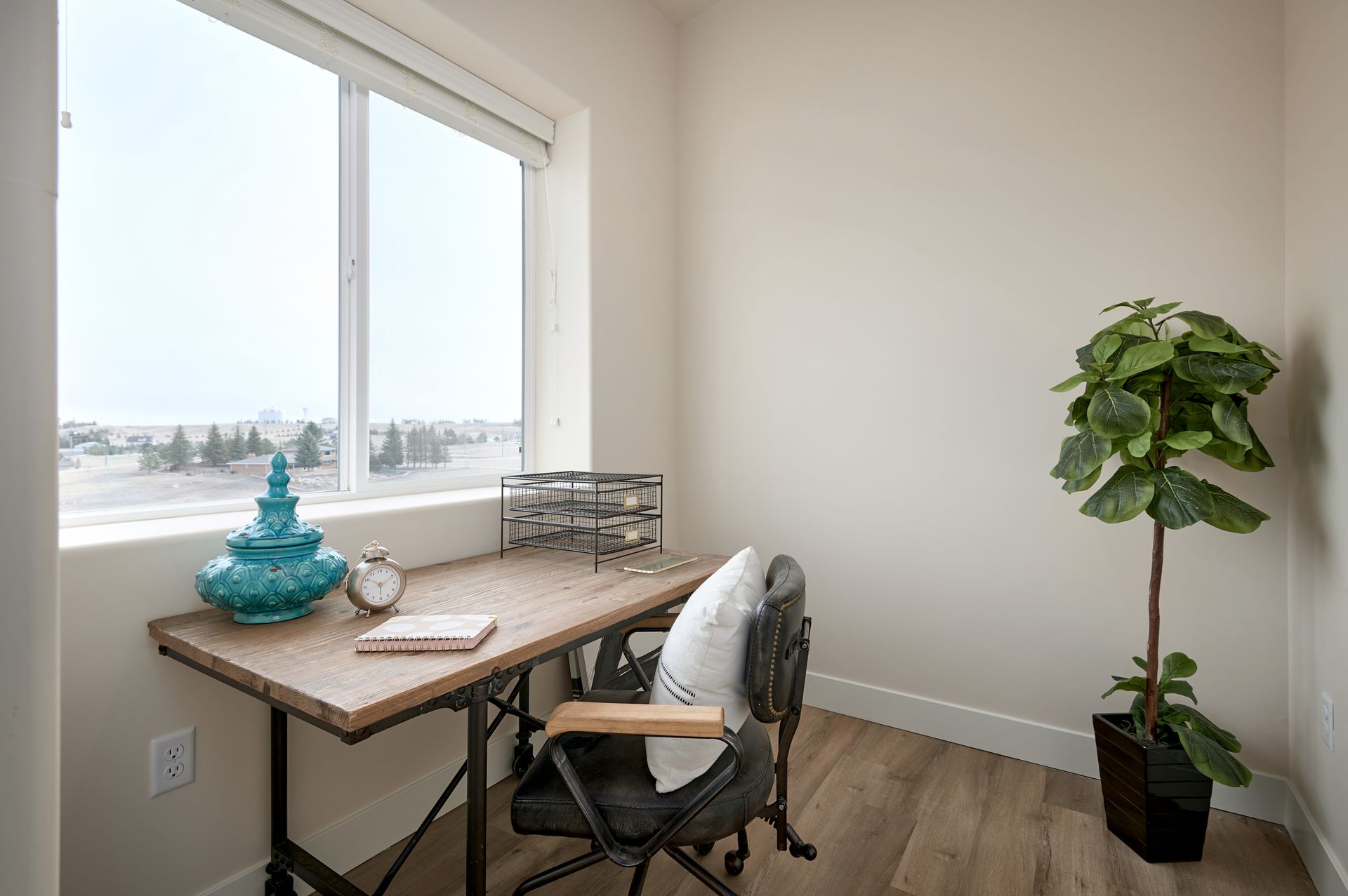 Small home office with desk by window, chair, turquoise decor, and potted plant