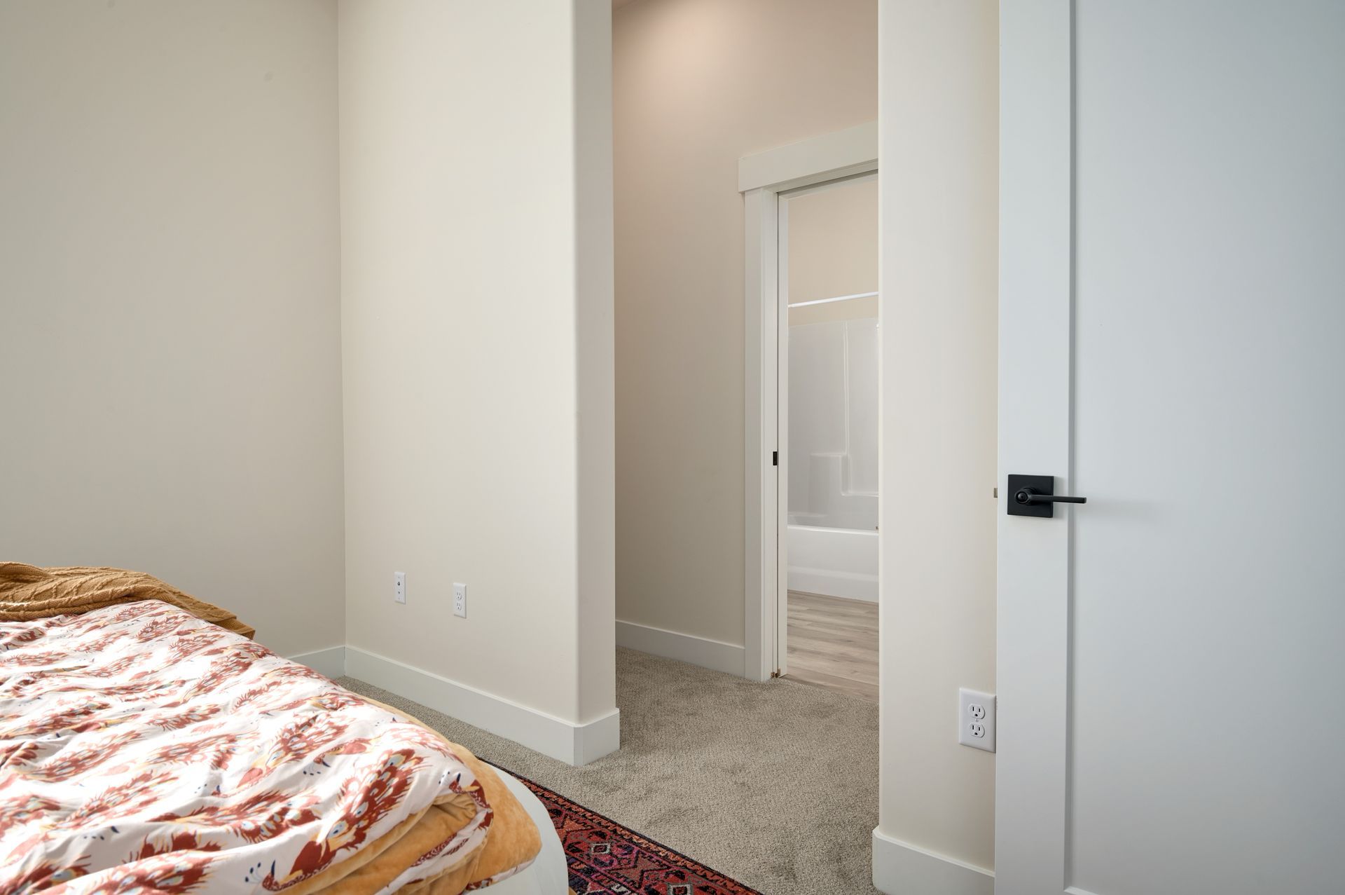 Bedroom with beige carpet, white walls, a bed edge, and an open doorway to a hall.
