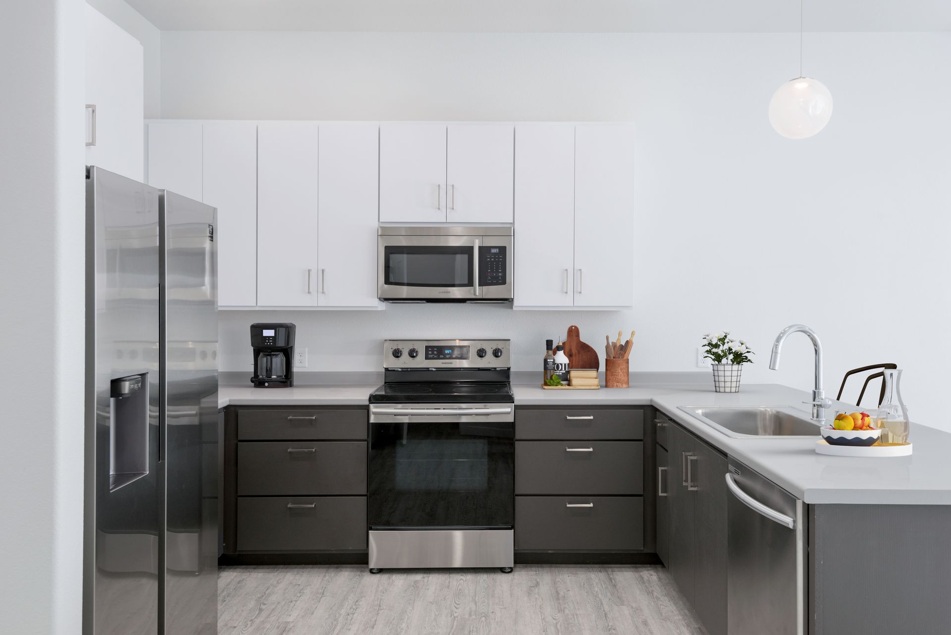 Modern white kitchen with stainless steel appliances, dark cabinets, and a breakfast bar