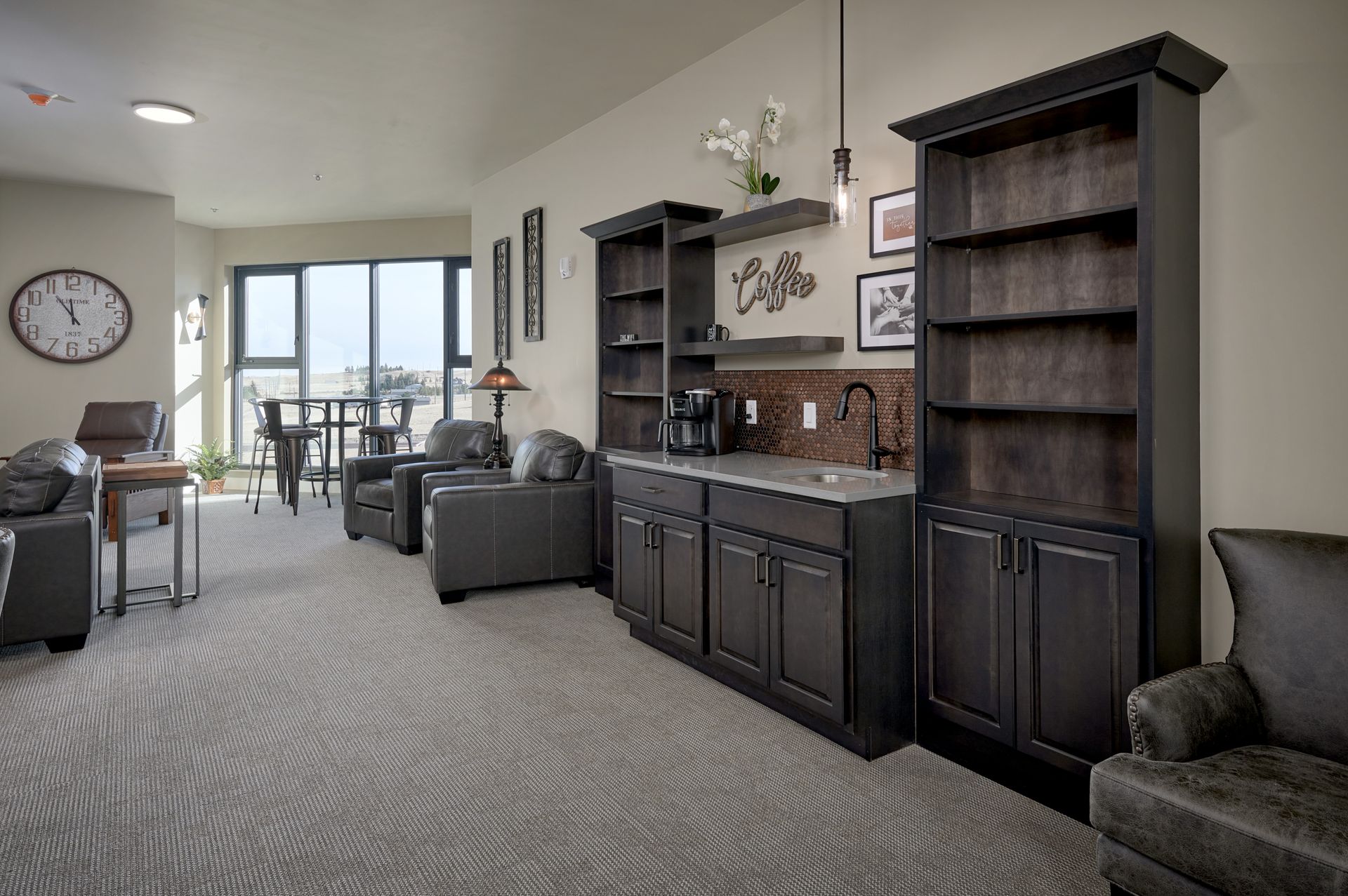 Living room with dark wood cabinets, gray seating, and large windows opening to a patio