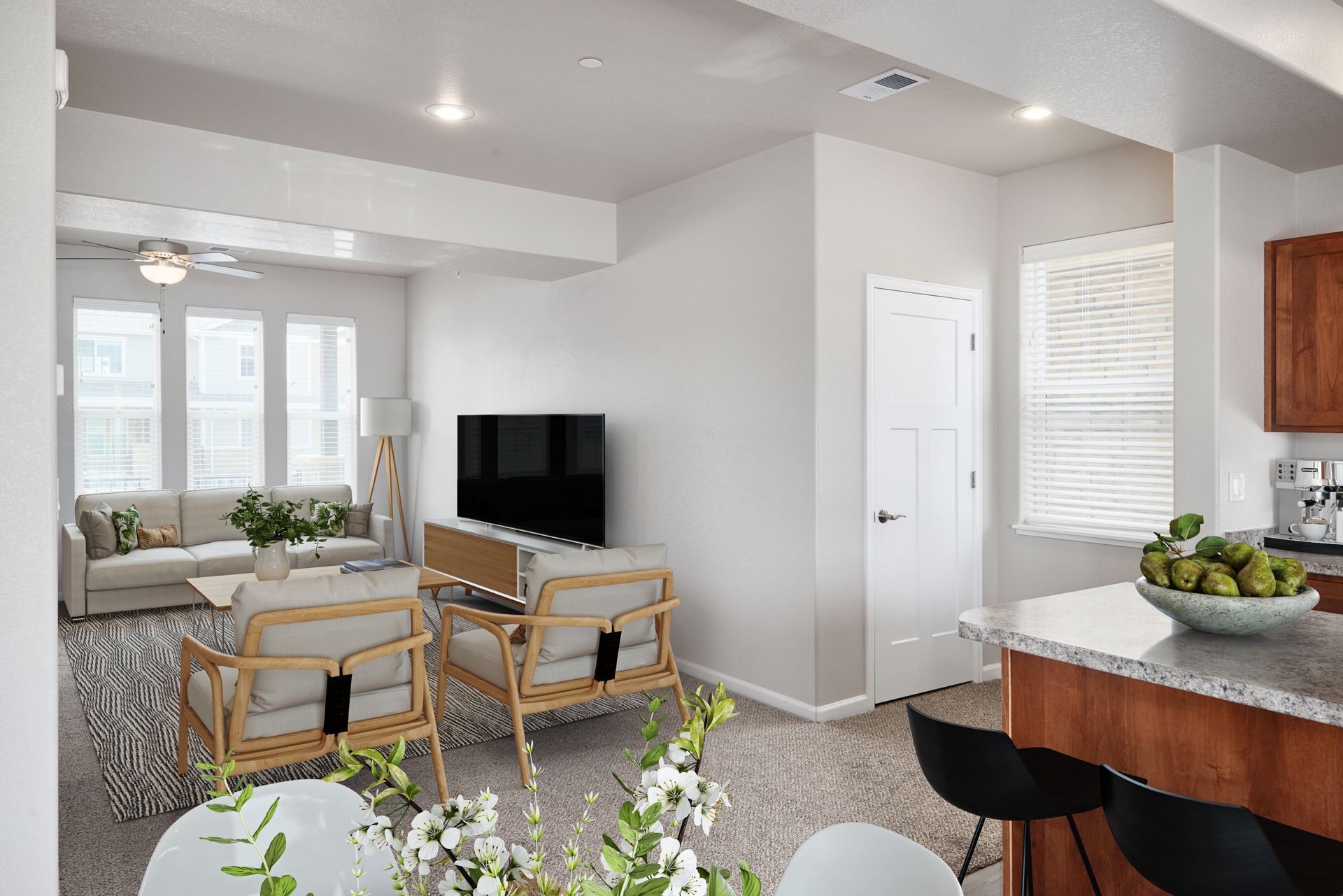 Bright open living room with sofa, TV, dining area, kitchen island, and large windows