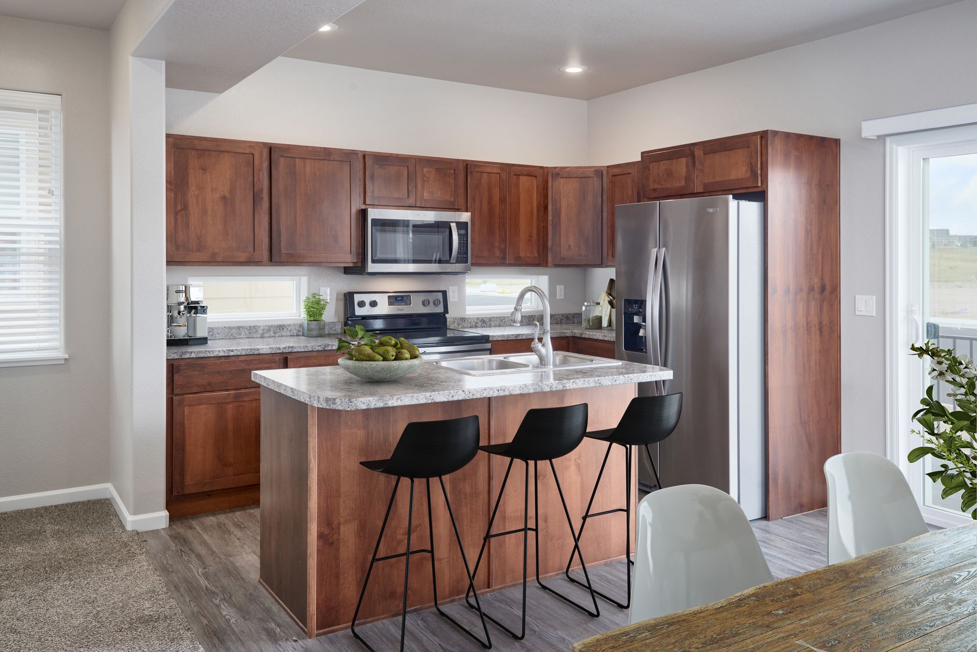 Modern kitchen with wood cabinets, stainless appliances, granite island, and two black bar stools