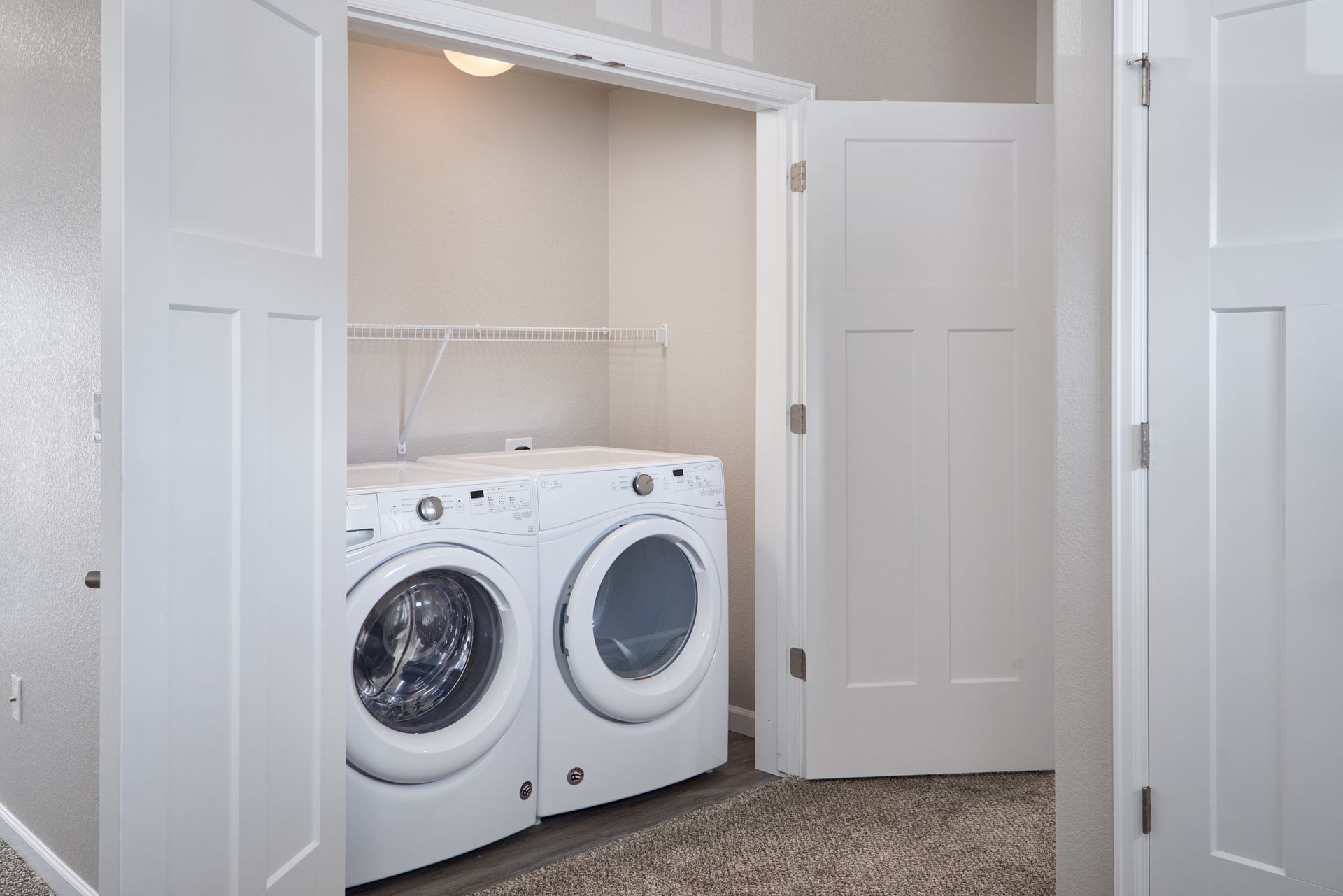 White front-loading washer and dryer in a closet with open double doors.