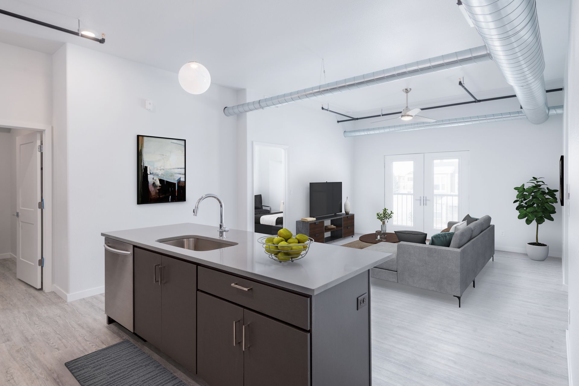 Bright modern loft with kitchen island, gray sofa, large windows, and exposed ductwork
