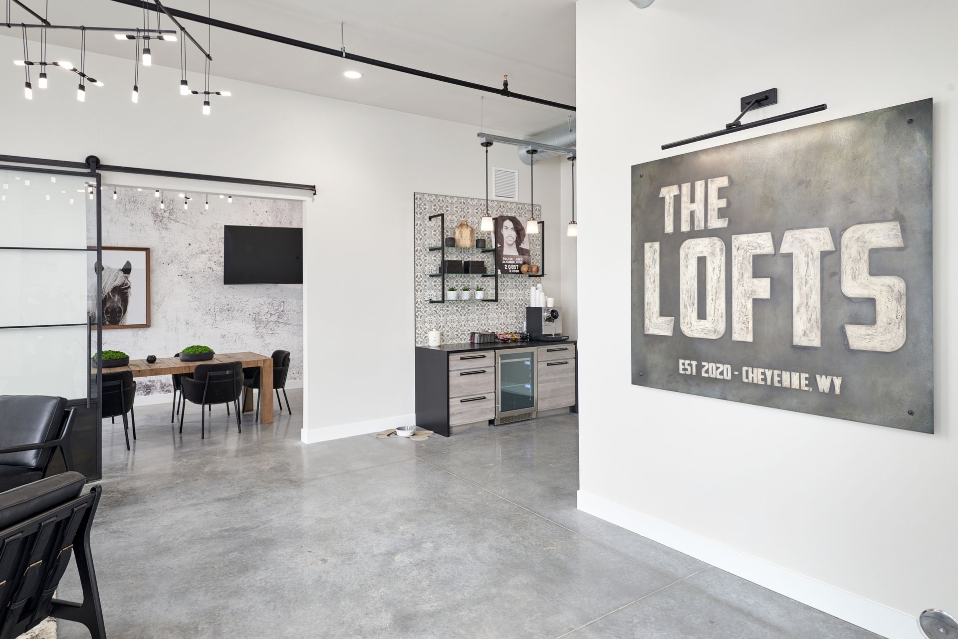 Loft-style office interior with concrete floors, desks, and a large wall sign reading “THE LOFTS”