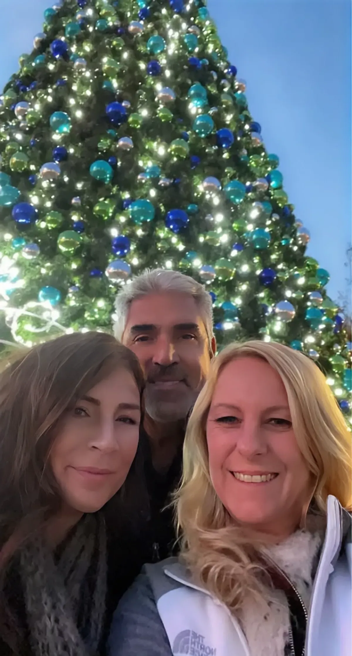 3 friends in front of a large, outdoor Christmas Tree