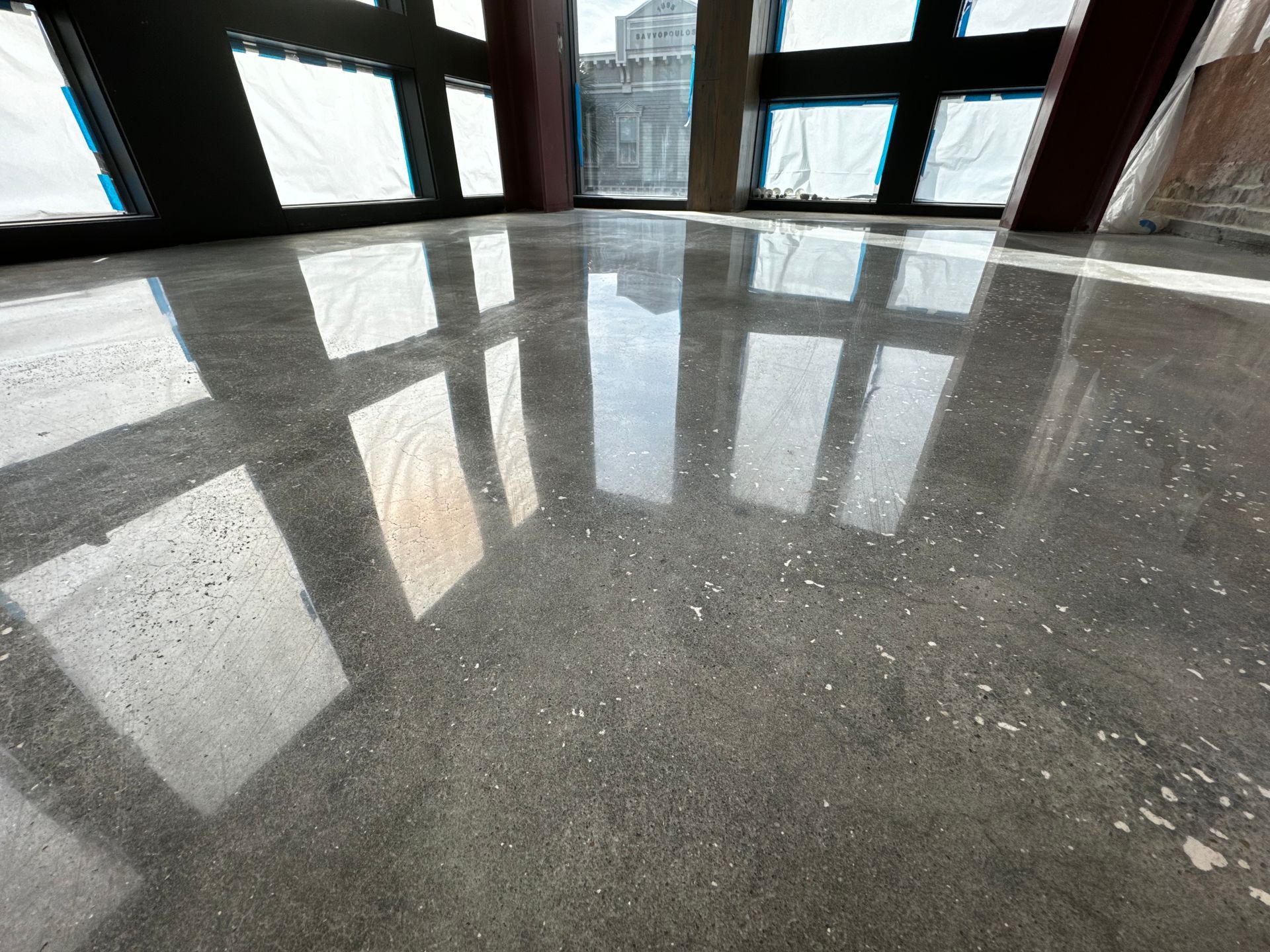 Polished concrete floor reflects large windows; room under construction.