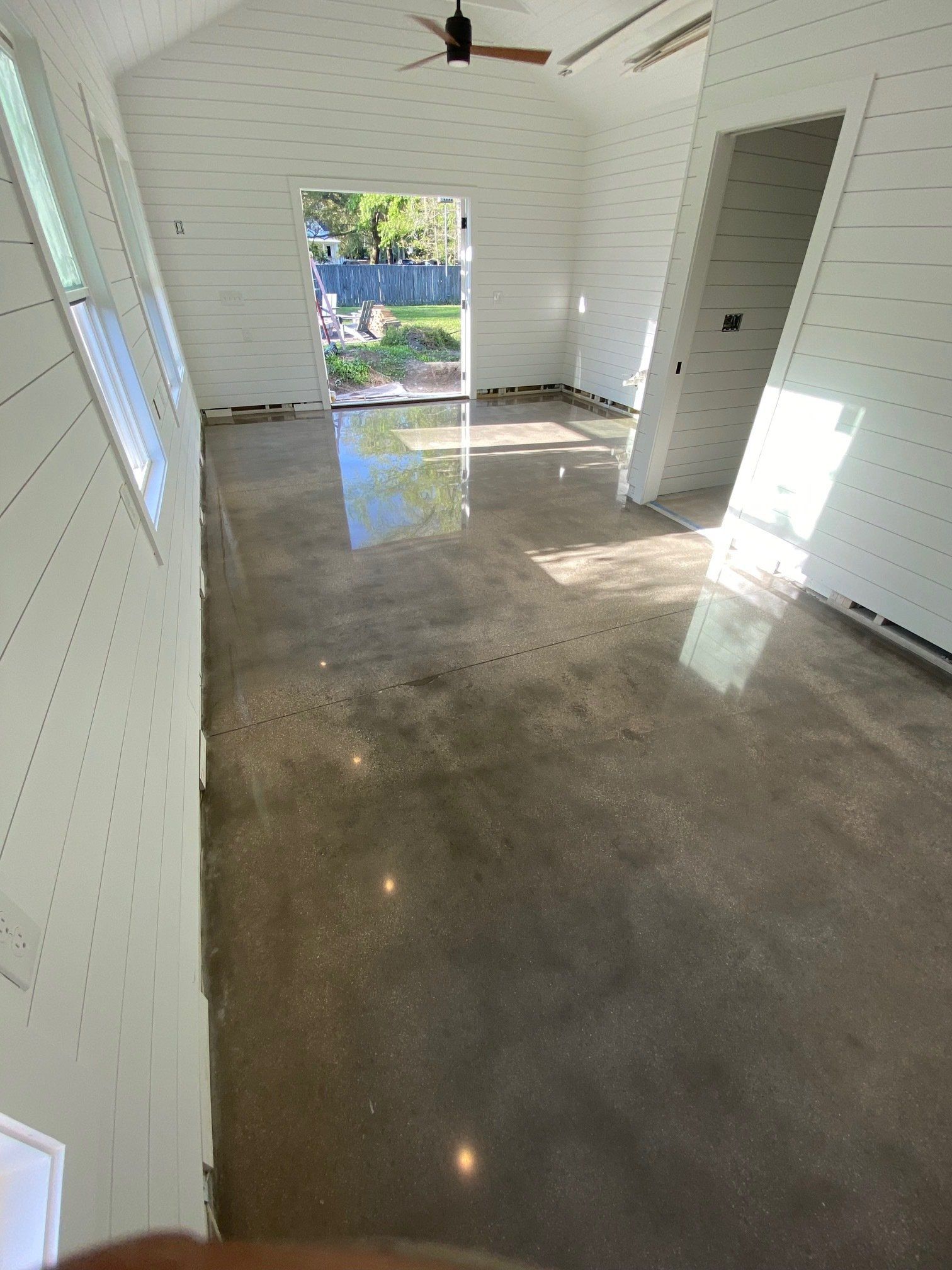 A light-filled room with polished concrete floors and white paneled walls. Sunlight reflects off the floor.