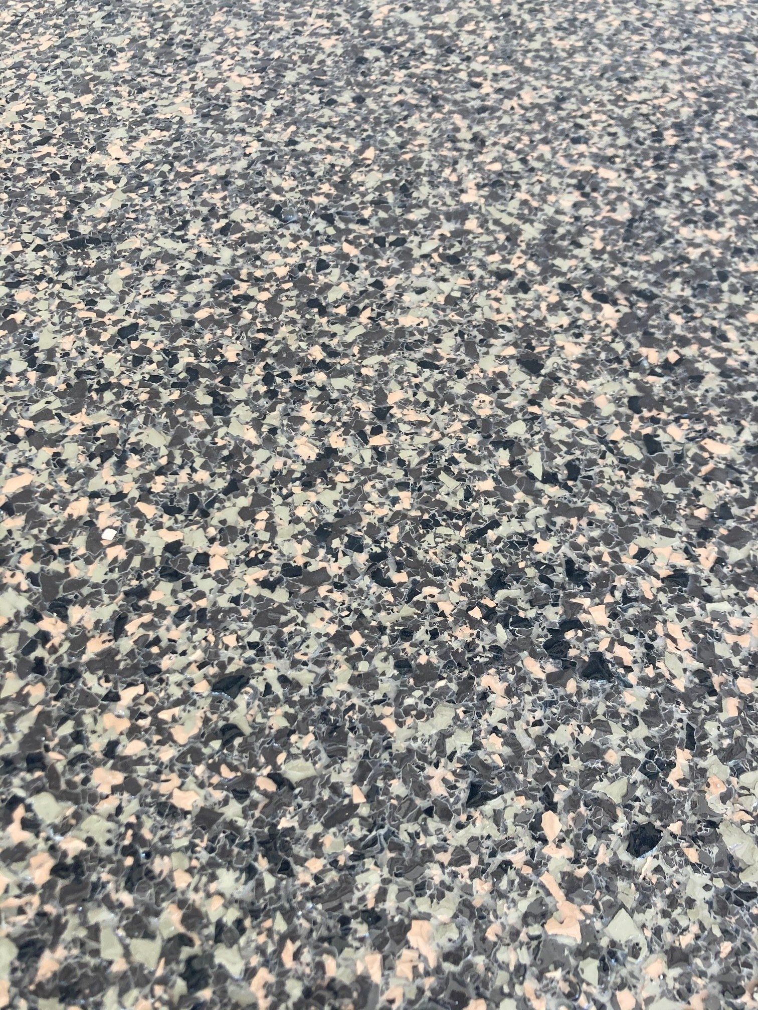 Close-up of a speckled floor with a mixture of white, gray, and black chips embedded in a smooth, glossy surface.