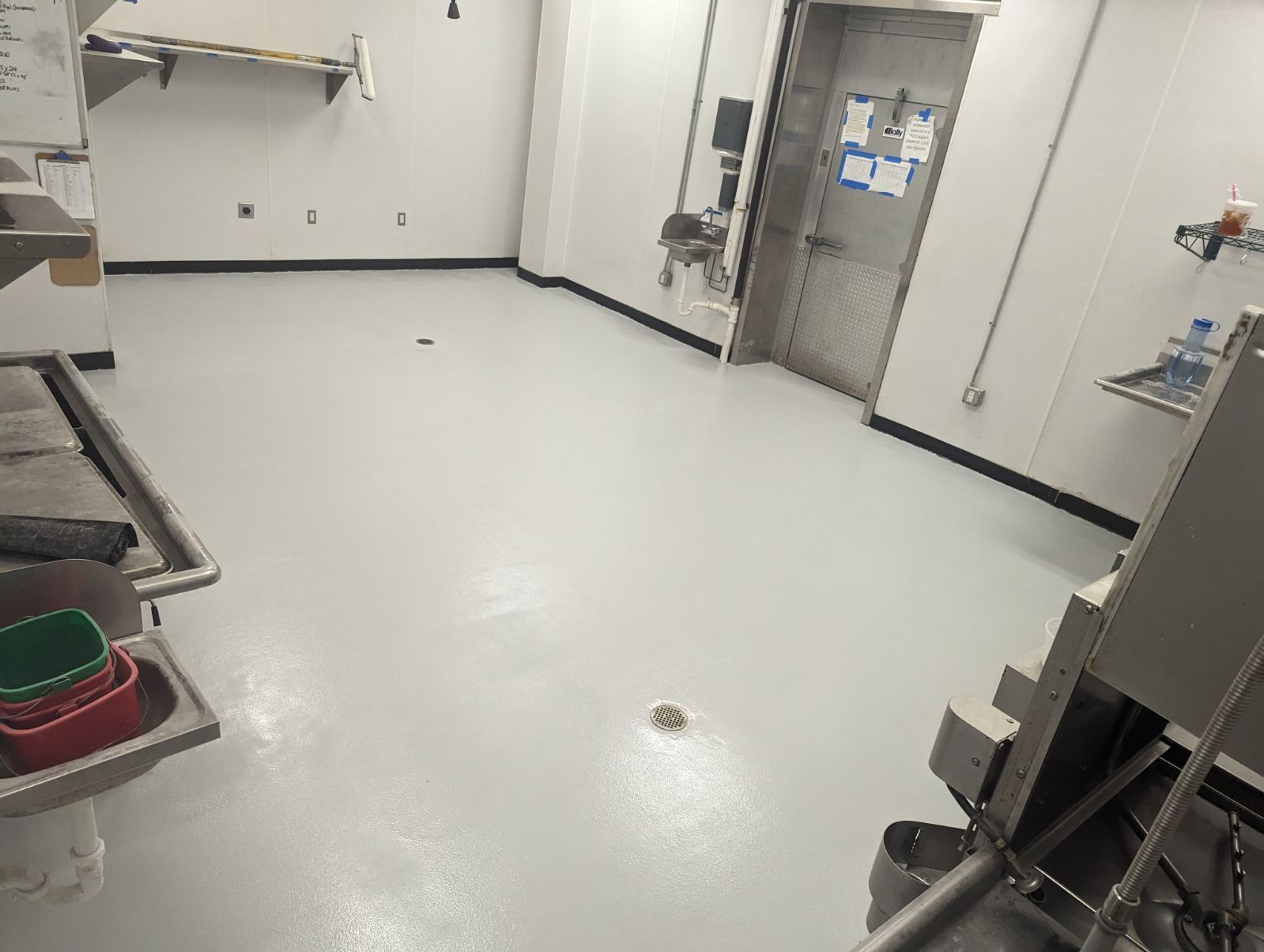 A clean, white-walled laboratory with a gray floor. Stainless steel sinks and equipment are visible.