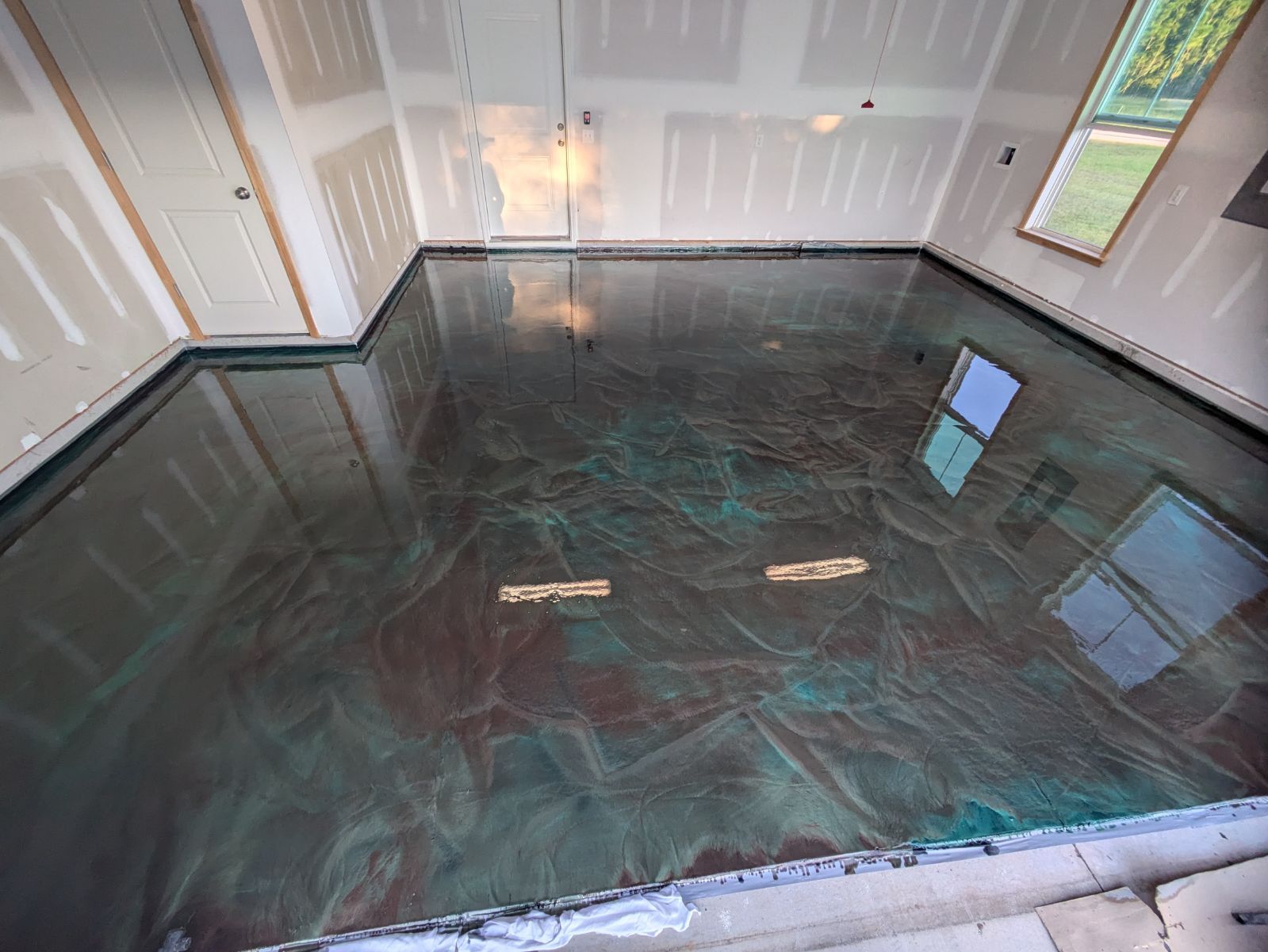 A shiny metallic floor in a garage with a reflection of windows.