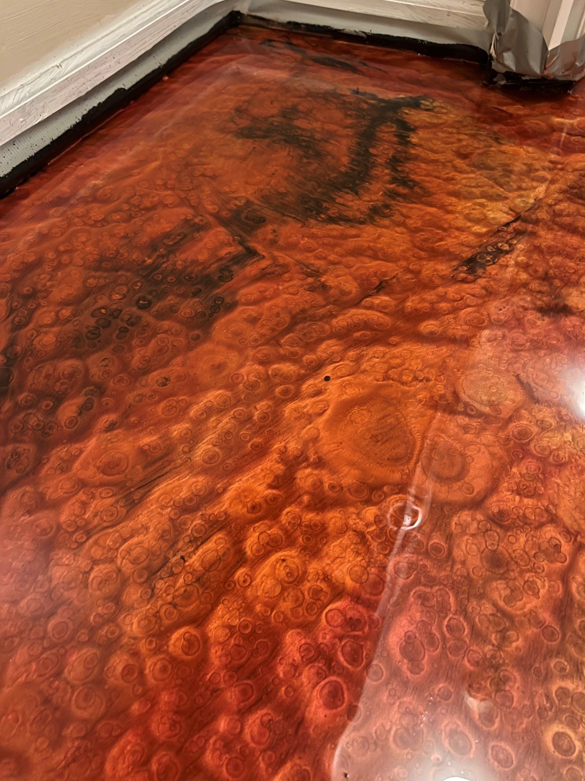 Metallic epoxy floor in shades of orange and black with a bubbly, lava-like texture.