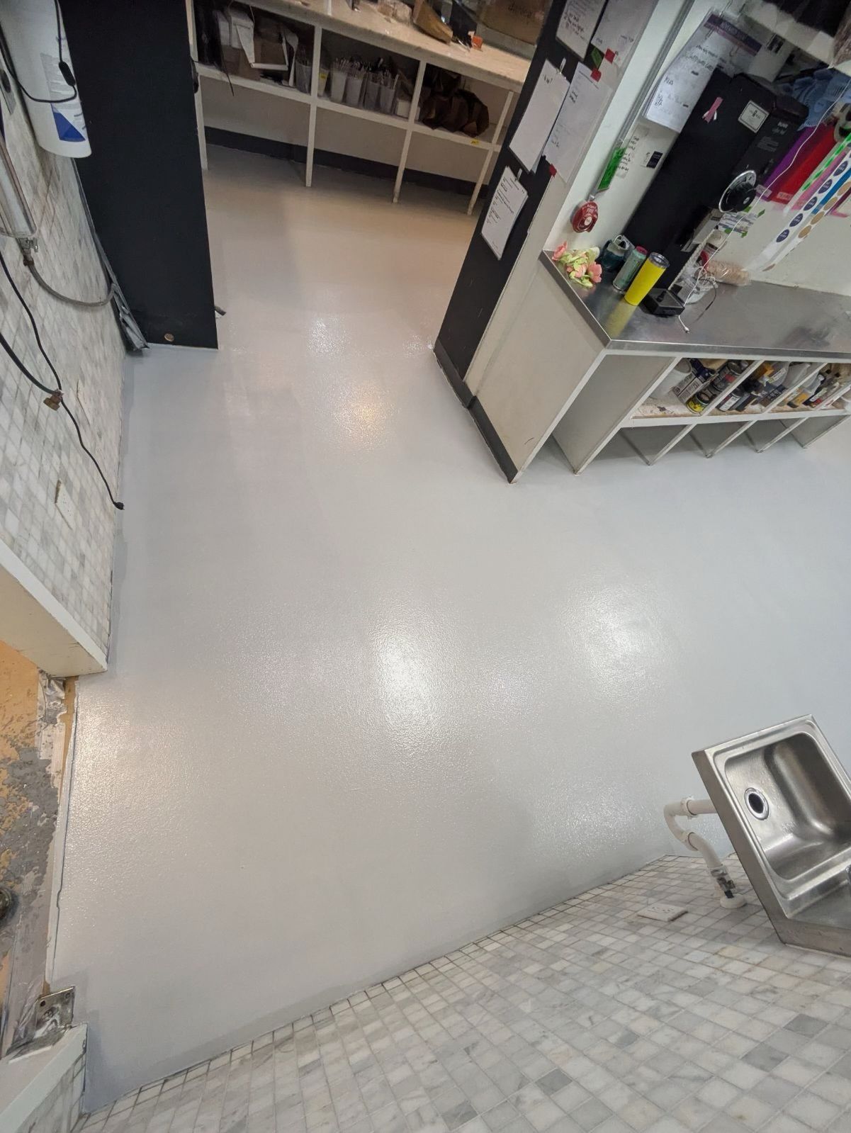 A kitchen with a white floor and a stainless steel sink.