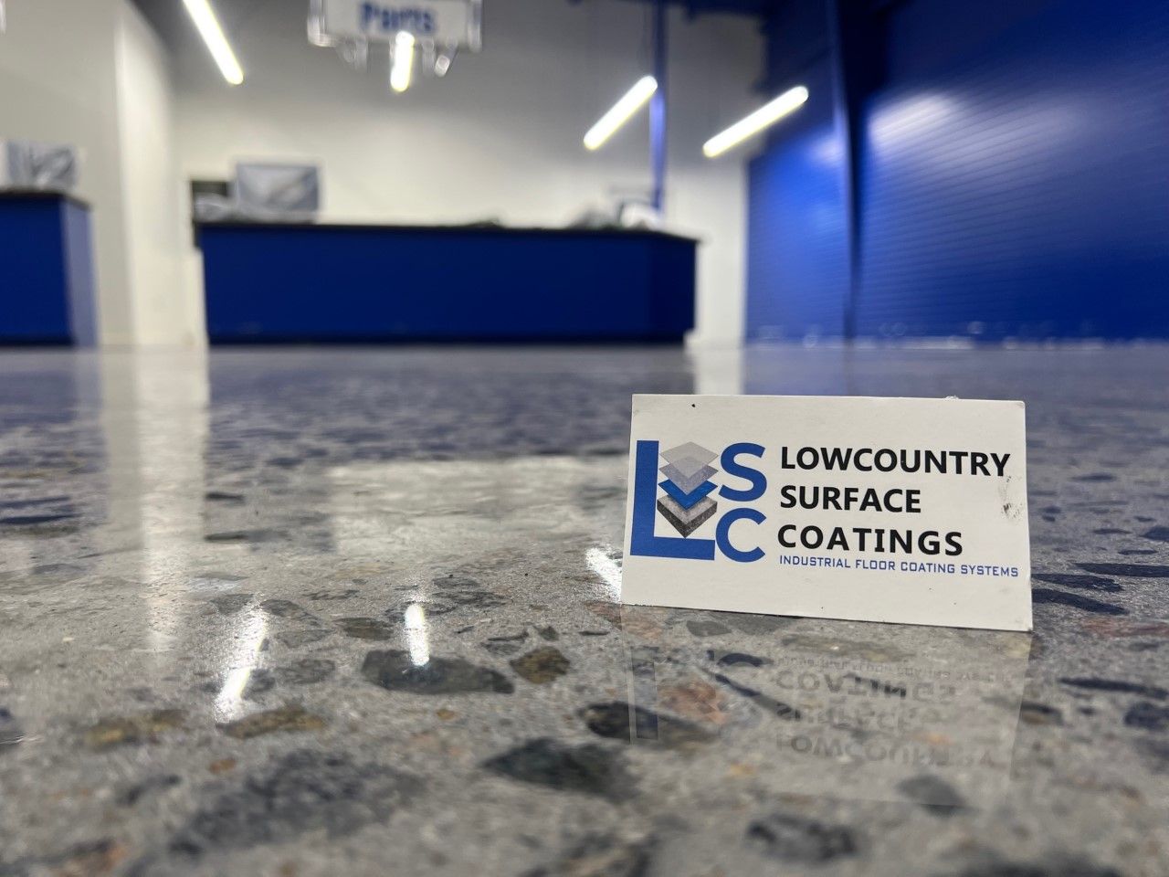 A glossy concrete floor with a business logo for Lowcountry Surface Coatings, with a blue and white interior.
