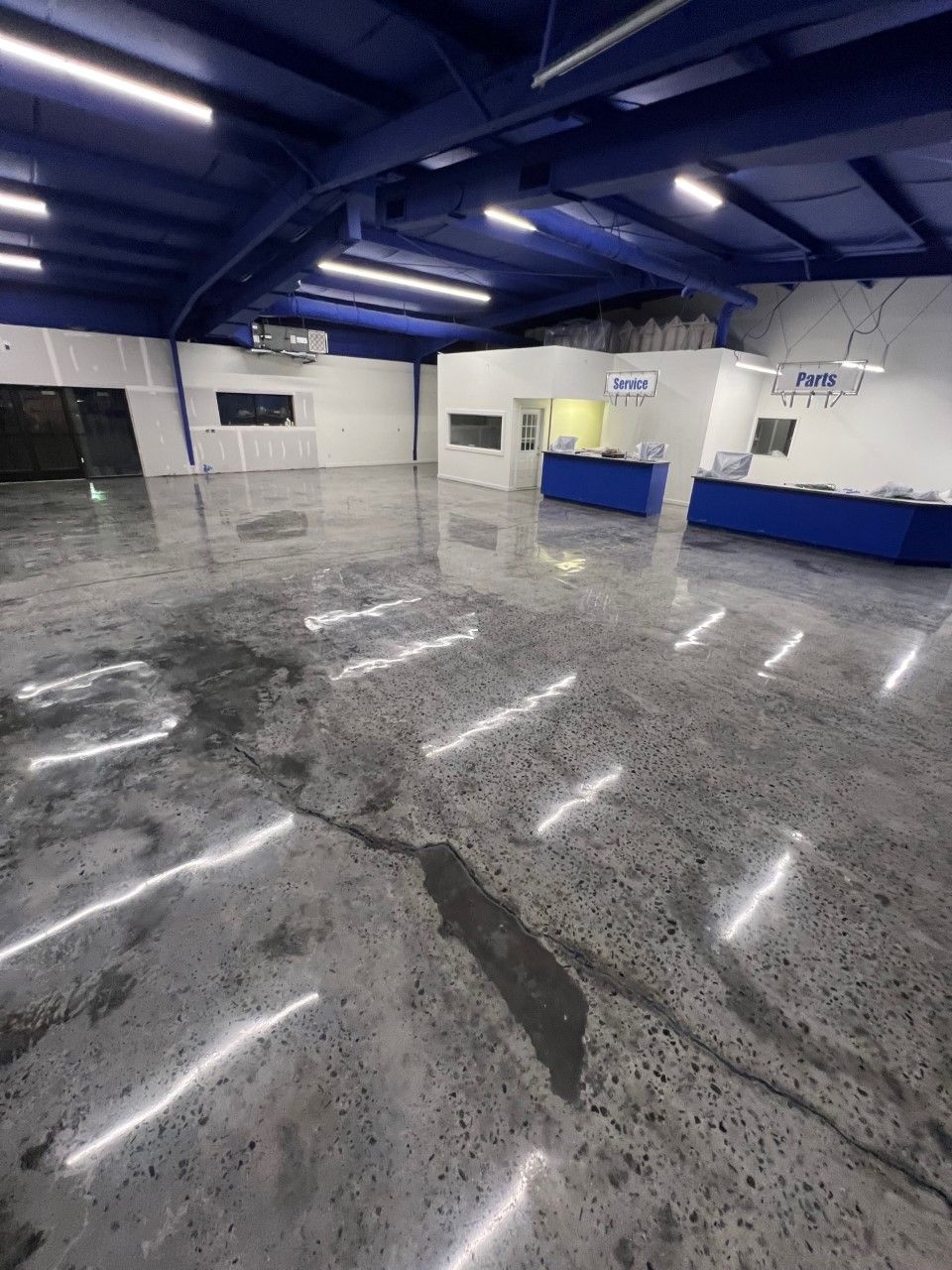 Large empty industrial space with polished concrete floors, blue ceiling and accents, and white walls.