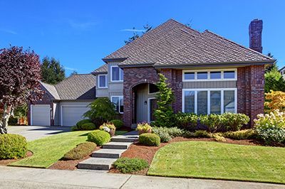 A large brick house with a lush green lawn in front of it.