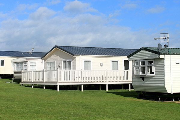 A row of mobile homes are parked in a grassy field.
