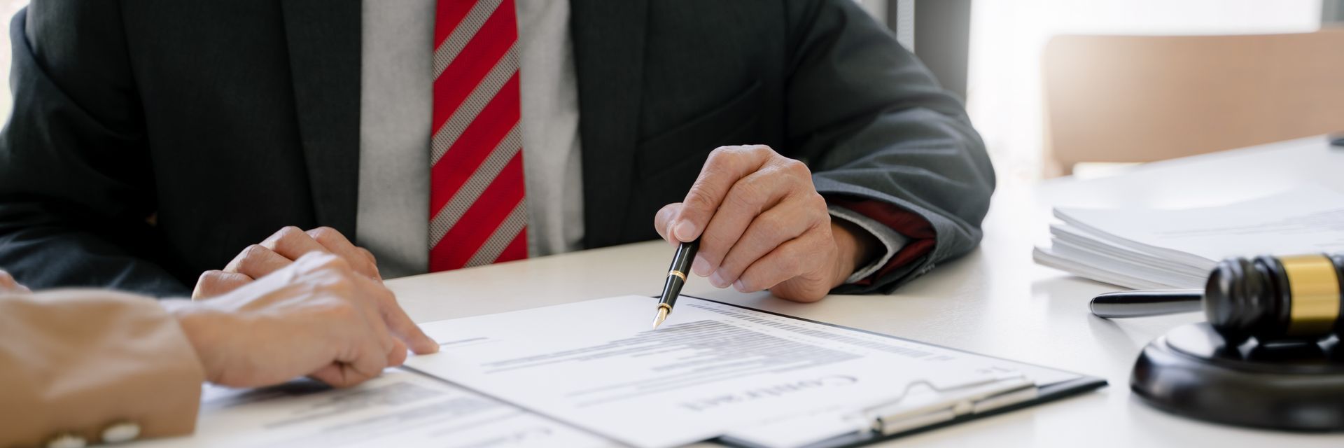 A man in a suit and tie is sitting at a table signing a document.