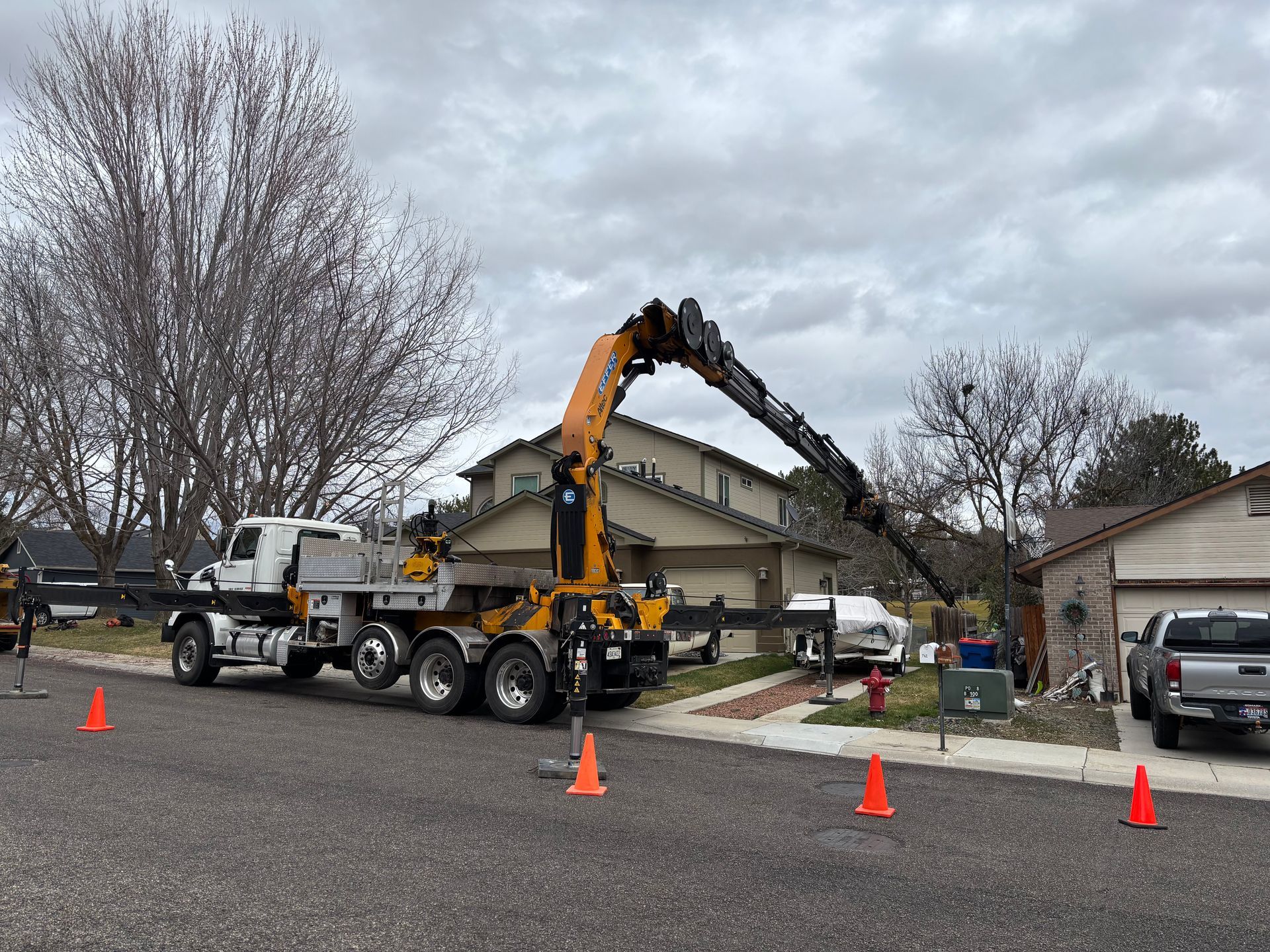 Utility truck with extended crane arm working on a suburban street — Tree Services in Boise, ID